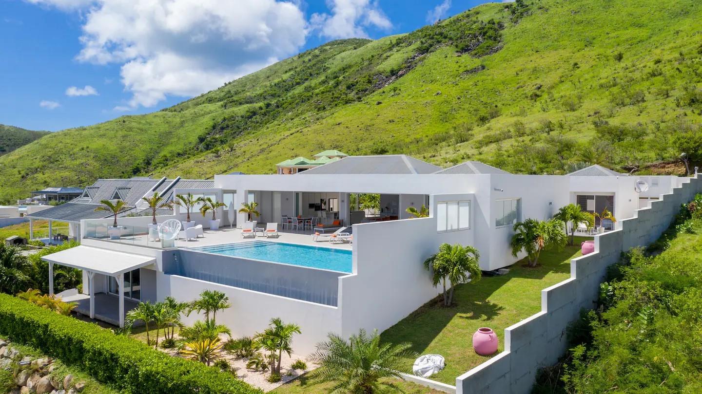 Channeling understated luxury and panoramic Caribbean beauty, this 350 m² contemporary villa is perched above the sea with sweeping views of St. Barth. Privately located at the end of a quiet cul-de-sac with secured access, the home is designed to frame the horizon from every room in a luminous, serene setting. The main residence features a triple split floor plan with 3 spacious en-suite bedrooms, while a separate apartment with private 70 m² sea-view terrace adds a 4th bedroom. The custom kitchen is fully equipped with high-end appliances including double ovens, and a wine cellar. Outdoors a 240 m² terrace surrounds the infinity pool, embraced by a lush tropical garden. This home offers both refined living and strong investment potential in one of the Caribbean’s most desirable enclaves.