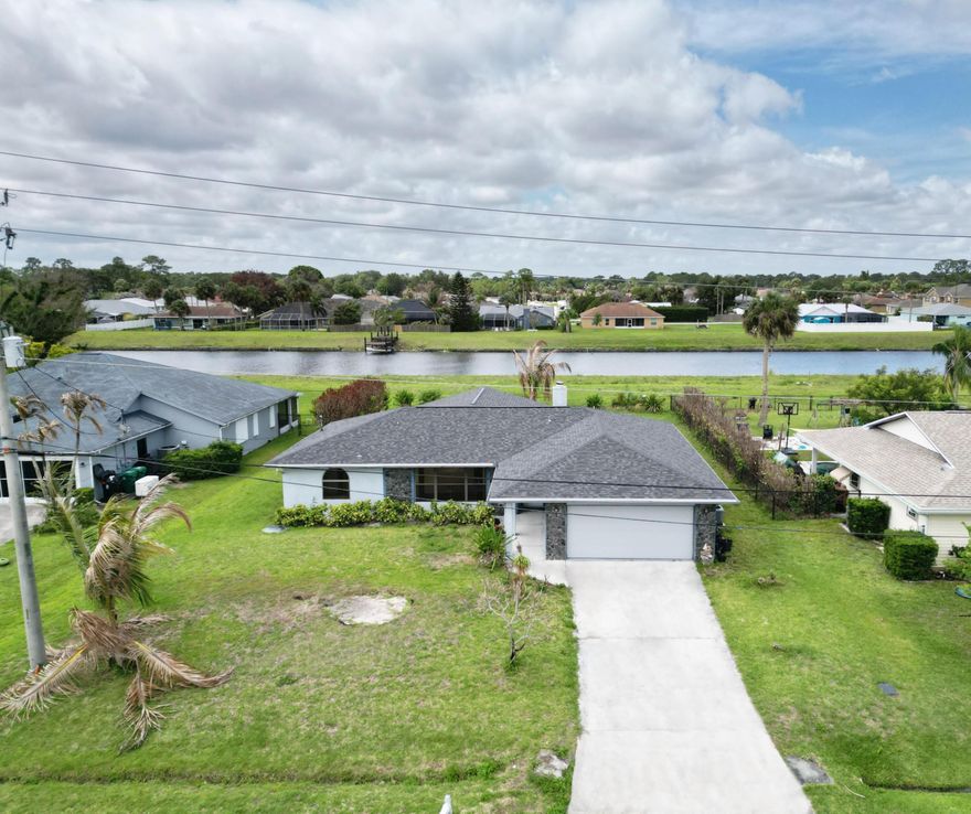 Great 3/2/2 home located on the C-24 Canal. This home sits on a quite street conveniently located minutes away from a variety of new restaurants, parks and shopping in the Tradition area. Brand new roof (2026). Embrace indoor-outdoor living with the sliders out to the enormous screen room looking out to the greenbelt and canal. A dock can be built. Split floor plan and vaulted ceilings. New laminate flooring throughout most of the interior. Large primary bed and bath with his/hers vanity, spa tub, water closet and standing shower. Home also has a fireplace and rainfall collection system.