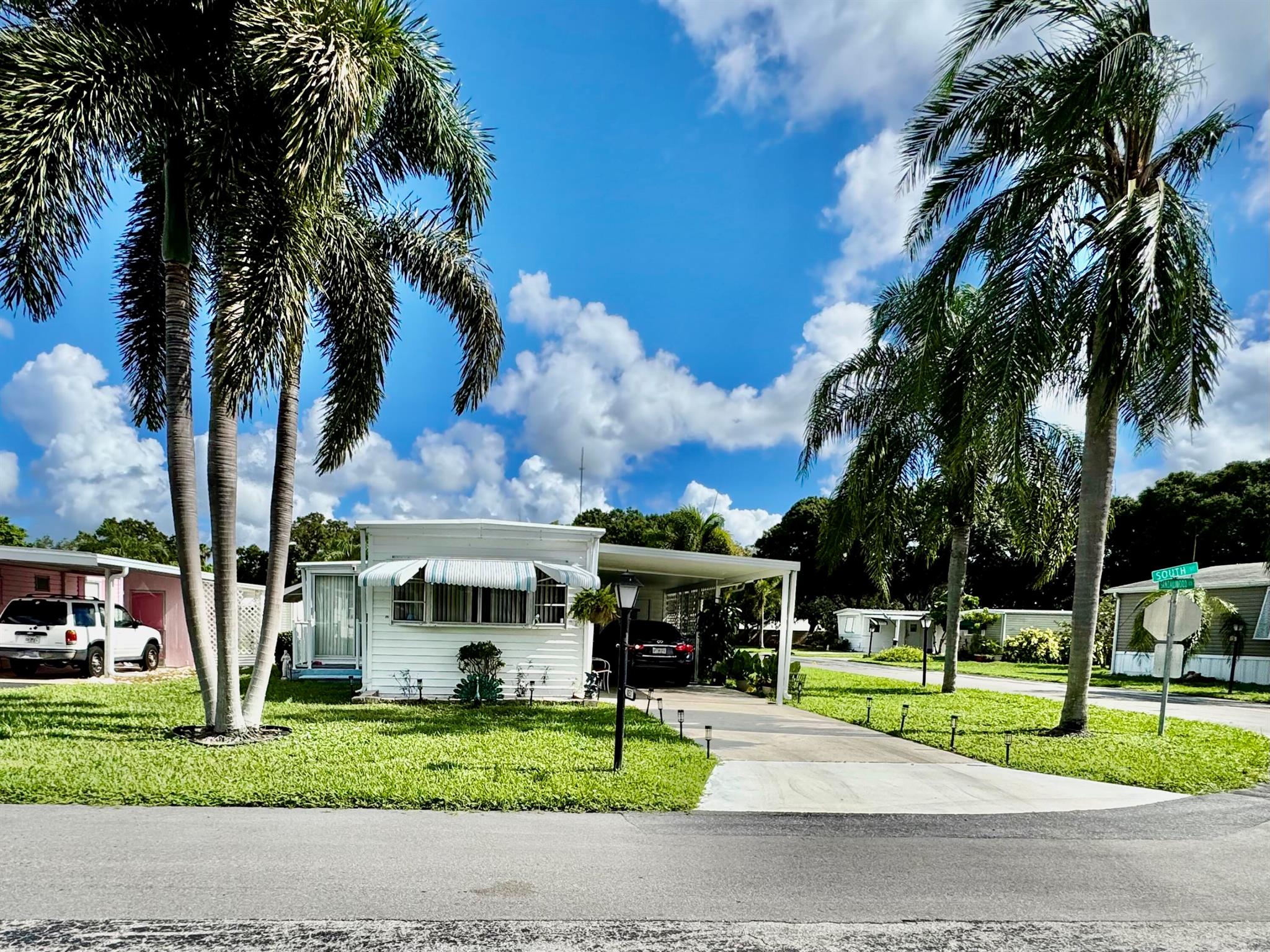 Opportunity knocks! This 2-bedroom, 1.5-bath handyman special sits on a quiet corner lot in the desirable Westlakes 55+ COOP owner community in Boca Raton. NO LAND LEASE, LOW HOA $225/MONTH. Featuring a spacious open layout, living room with an extension bump out, a enclose Florida room with window and screen, a good size shed, and carport to cover you vehicule, it's ready for your personal touches. A roof over to protect the roof from hurricane weather as been installed.Welcome to Westlakes, a beautifully maintained, friendly mobile home community in Boca Raton, FL. This 55+ active adult neighborhood offers a safe, serene environment with well-manicured streets, abundant greenery, and a sense of community.