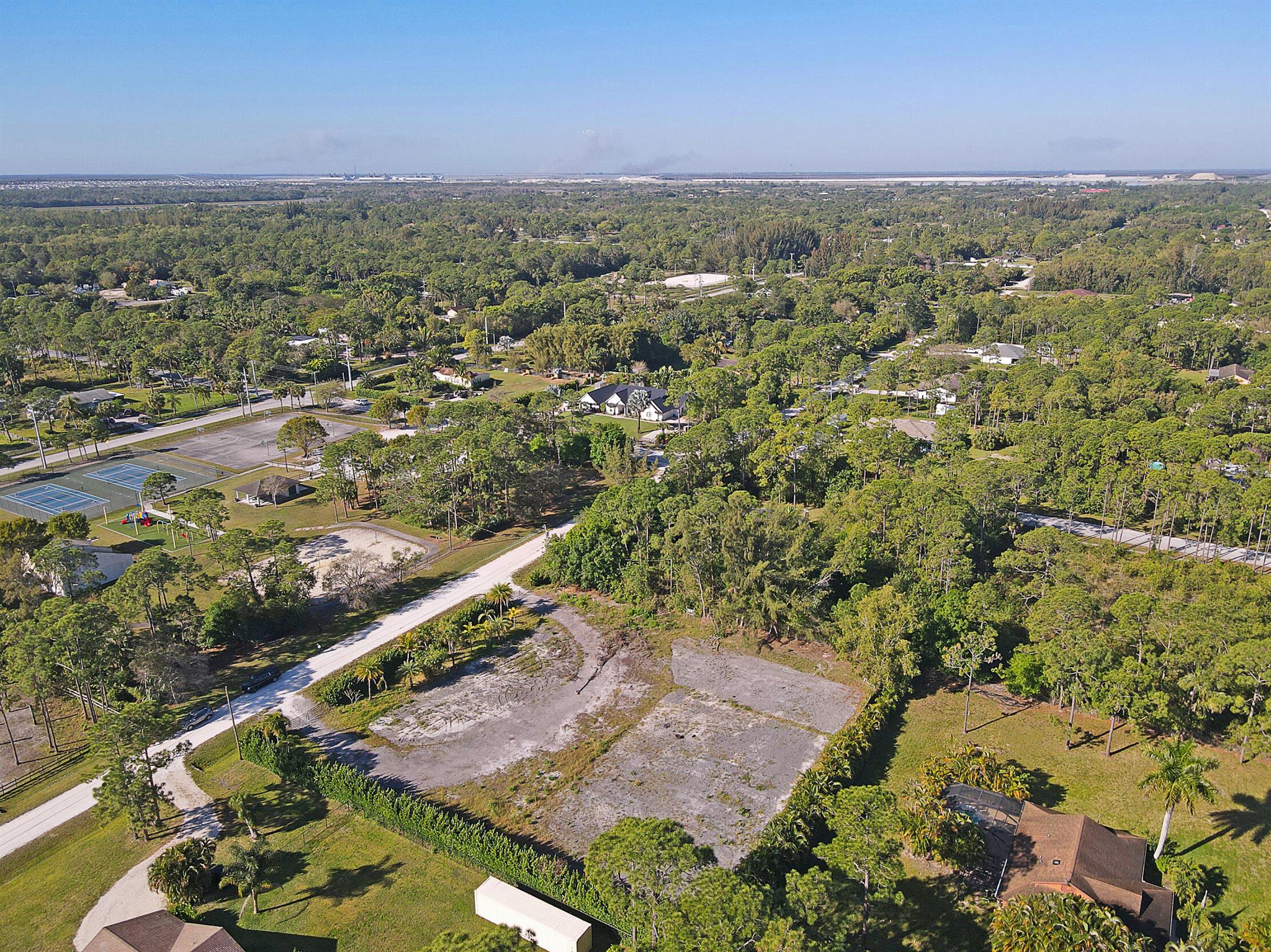 Over one acre paradise! Across from a park including a playground and workout area w/ artificial turf, paddle sports backdrop, two tennis courts, basketball courts, covered picnic area with tables, 2 bathrooms and parking lot.This property has been cleared and filled, has a milled circular driveway, double swing gate entrances with cameras.Palm trees, bamboo and over 350 ft of Clusia Hedges surround the property for privacy. No HOA restrictions--ideal for horses and chickens.Short drive to schools, stores, amenities and Lion Country Safari. Any builder can build! Park your Rv's, Campers & trailers while you build your dream home. Can park your boat! Meter power available, sump pump for drainage, and a generous well.