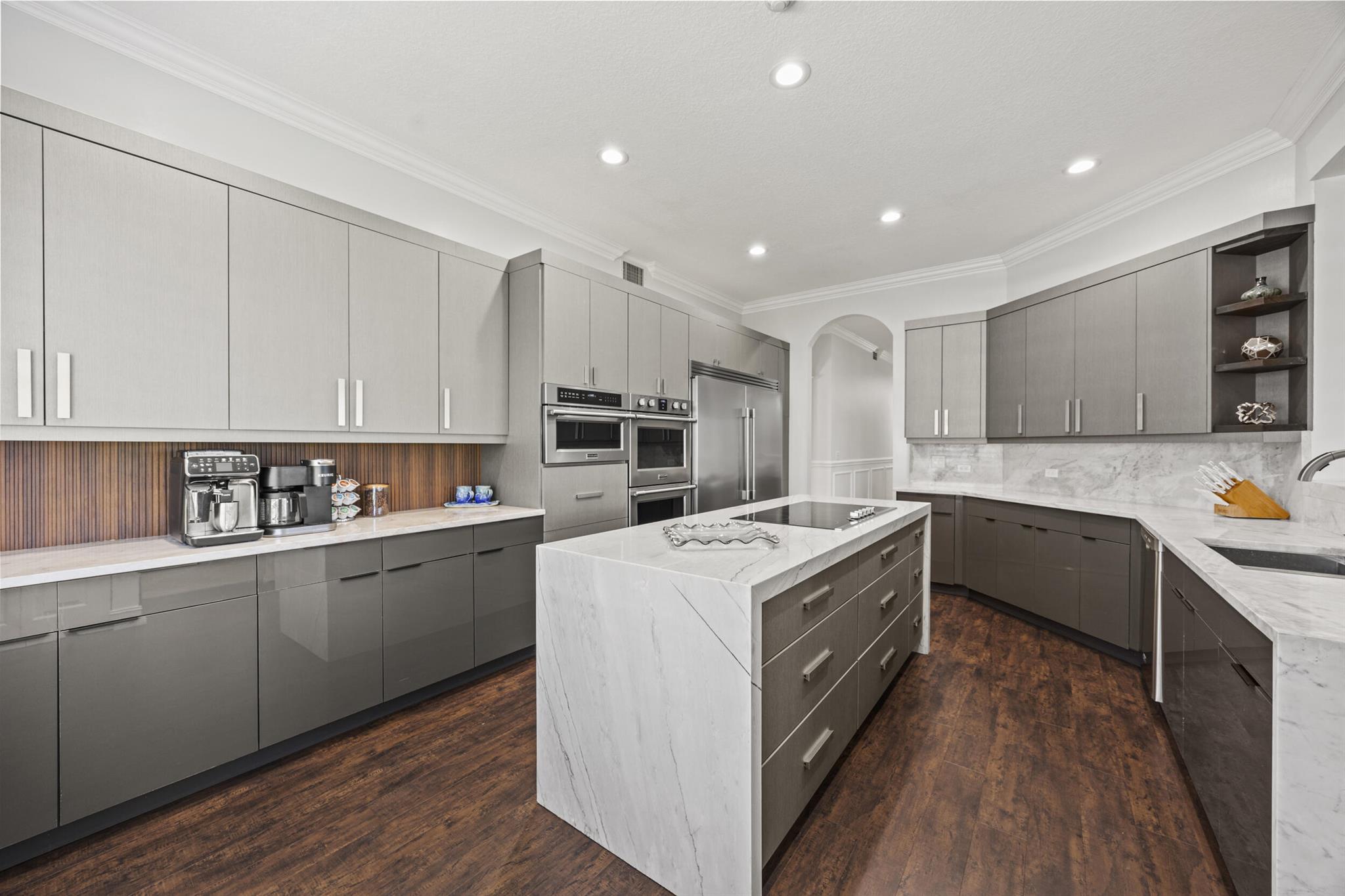 Spectacular golf course view and a fully renovated custom kitchen make this first-floor luxury condo with impact windows a special find. With nearly 2,400 square feet of living space, this 2BR/2BA + DEN home is a must see. Recent renovations include a redesigned kitchen which enhances the great room concept, flow and functionality of the entire space. Luxurious quartzite countertops, Frigidaire Professional appliances, undercabinet lighting, coffee bar and reverse osmosis system are just a few of the things that make this contemporary kitchen a chef's dream. The beautiful and functional dry bar compliments the large open living space, as does the well-appointed dining room. Gorgeous wainscoting, crown molding, millwork, and bright white plantation shutters throughout. Much desired wood
