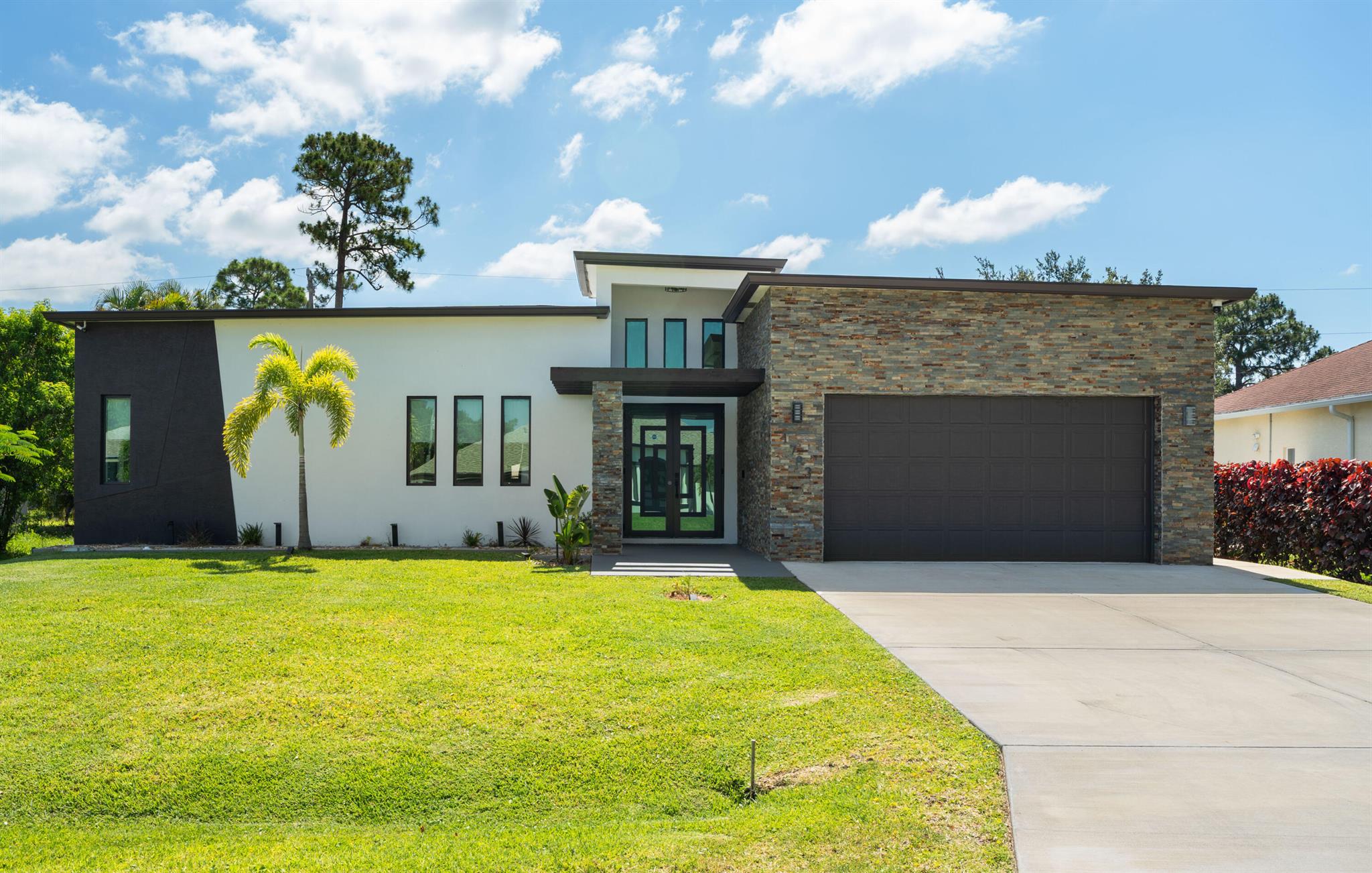 Modern design and custom craftsmanship meet in this 2023-built 4 bed, 4.5 bath home in Port St. Lucie, offering fresh appeal, refined comfort, and elevated style. Skylights throughout fill the home with natural light, while polished marble-look tile and clean finishes create a bright, inviting aesthetic. The spacious kitchen with large island anchors the open living area, and a full pocket slider opens to the screened patio for seamless indoor-outdoor living. Each bedroom features a private en-suite, ideal for guests or family. Outside, a fenced yard blends garden beds, wood decking, pavers, and fruit trees into a thoughtfully designed space. Impact windows, doors, and energy-efficient icynene insulation add lasting value. Move-in ready with the feel of new construction without the wait.