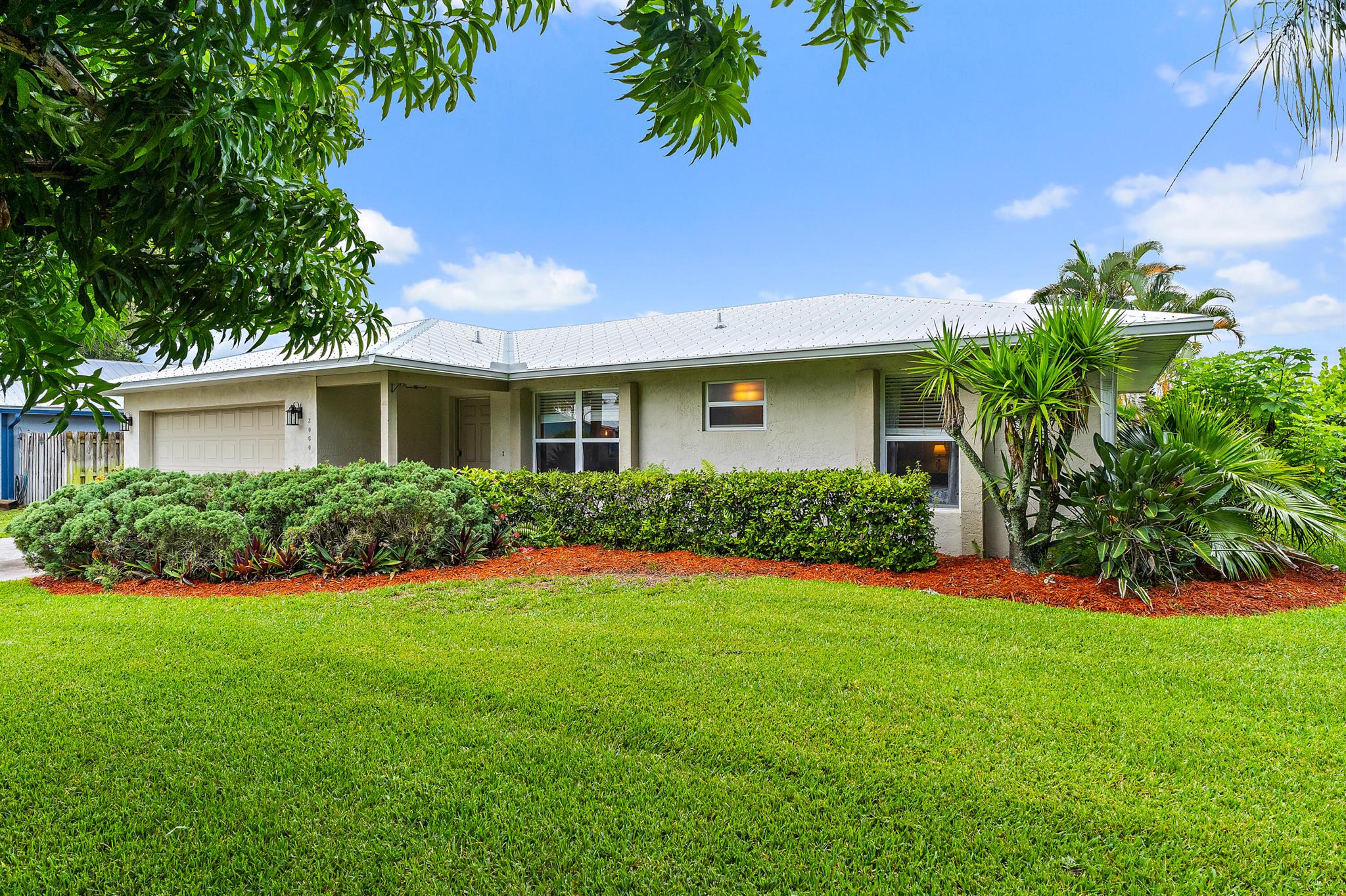 This beautifully maintained property is ideally located in sought-after Jensen Park Estates, minutes from the Indian River and Jensen's pristine beaches. Built with solid CBS construction, the 3-bed/2-bath/2-car garage home offers numerous upgrades: NEW 2024 Metal Roof, Gutters, Soffits, 2023 Water Heater, Irrigation, Lighting Fixtures, AC update, washer, dryer, dishwasher, and more! LOW HOA welcomes Boats and RVs. The three bedrooms offer generous walk-in closets. The timeless kitchen, with a convenient pass-through to the 300 square foot Lanai, is ideal for indoor-outdoor living complementing the spacious great room. The backyard will easily accommodate a pool, while a mature mango tree in front provides charm and privacy. With complete storm protection, you will enjoy peace of