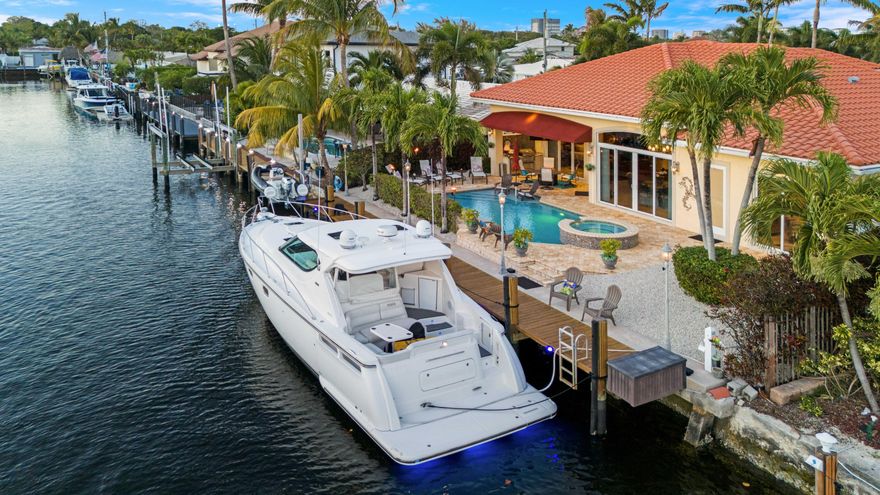 Set along a wide 100-foot canal, this stunning waterfront 4-bedroom, 2.5-bath residence offers 70 feet of pristine waterfront with only one fixed bridge, a private dock, and a heated salt water pool for true indoor-outdoor living. Boating features include a 5' x 65' pressure treated dock and a 70-foot concrete seawall with king and batter piles and newly sealed and grouted seawall. Enjoy easy access to open water with an approximate 25-minute boat ride to the Hillsboro Inlet and about one mile to the beach by car. Inside, 2,252 square feet of living space showcases solid marble flooring with custom inlay, soaring 14-foot ceilings in the main living area, tray ceiling details, eight-foot solid wood doors, crown molding, and integrated accent lighting throughout. The main living space is anchored by a 13-foot custom entertainment center with granite top, creating an inviting and polished atmosphere. The kitchen is designed for both entertaining and everyday use, featuring custom Brazilian cherry cabinetry, granite countertops and backsplash, newly installed pot filler, and a new GE range and dishwasher. The large island with seating for four, a built-in hutch, wine bar with wine cooler, accent lighting, and a gas line available makes this kitchen a chef's dream. The primary suite serves as a private retreat, offering tray ceilings, separate his and her walk-in closets, and a spa-inspired bathroom with dual vanities, a custom mapped marble shower inlay, private water closet with Kohler fixtures, and a garden tub finished in granite and marble. Built in 2009 to meet Broward County's strictest building codes, the home features solid concrete construction, FULL PGT impact windows and doors, a concrete barrel tile roof, and a long-lasting elastomeric exterior finish. Outdoor living is enhanced by imported Turkish marble pavers, lush landscaping, and a custom built summer kitchen. Additional upgrades include a finished two-car garage, whole-house audio system with Alexa integration, built-in surround sound, central vacuum system, monitored security, water and temperature systems, high-efficiency two-stage Rheem AC installed in 2023 and a brand new Rheem Gladiator Smart water heater. A rare waterfront find just minutes from the beach and near the future Pompano Beach Downtown district, this home offers an exceptional lifestyle and strong investment potential. The new downtown will feature nine acres of green space, a central waterscape, and a vibrant, walkable community filled with shopping, dining, entertainment, and cultural events - a transformative addition set to redefine the area and elevate property values.