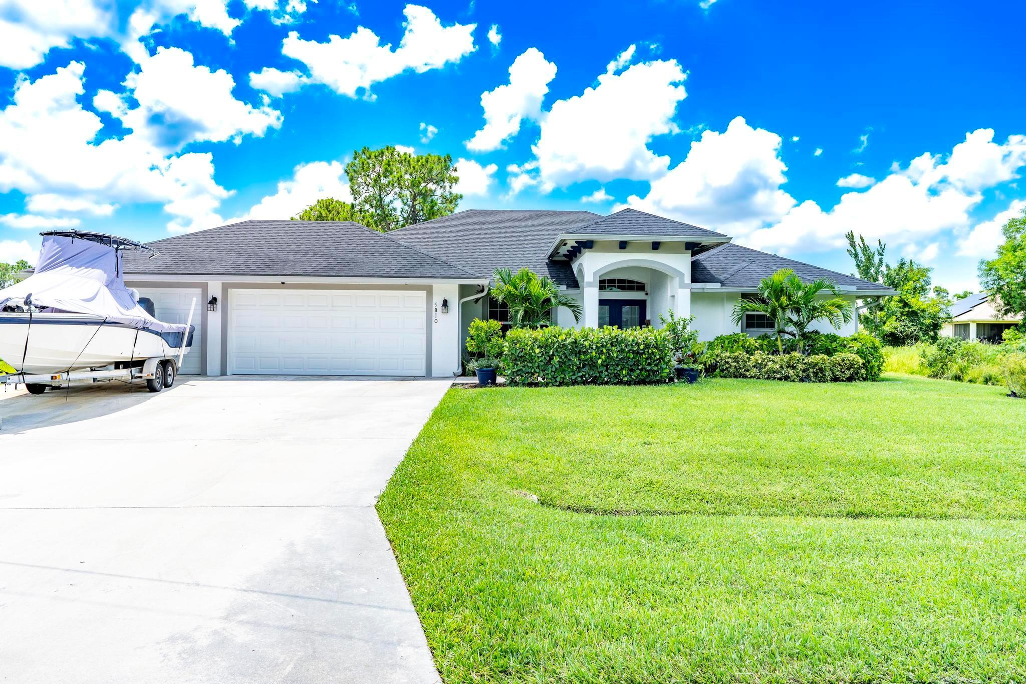 Welcome to your own piece of paradise in Port St. Lucie! This immaculate 2021 4-bedroom home by Grande Construction offers stunning tropical curb appeal with manicured landscaping, vibrant palms, and a grand columned entrance that immediately sets a tone of elegance. Features include impact windows & doors, custom coffered ceilings, crown molding, tile flooring throughout, and a spacious master suite with custom closets and a large tiled walk-in shower. The gourmet kitchen boasts wood cabinets, quartz countertops and backsplash, and under-cabinet lighting. Enjoy outdoor living at its best with a heated, salt water pool and a summer kitchen/tiki bar with two refrigerators and built-in grill--perfect for entertaining and enjoying the Florida lifestyle. Impeccably maintained and move-in ready