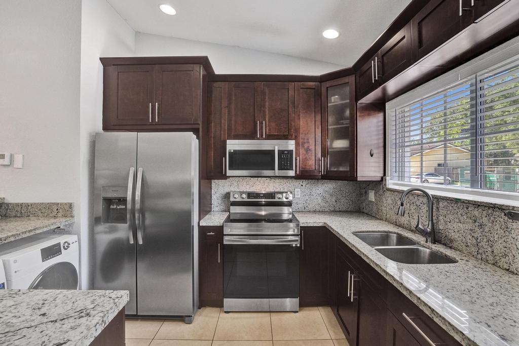 This beautifully maintained, modern one story townhome in a gated neighborhood features a 2 bedroom 2 bath corner unit. The open concept floorpan offers bright living and dining area with high ceilings and tile flooring all throughout the home with updated light fixtures. The kitchen is equipped with ample and soft close cabinet space, granite countertops, updated appliances, recessive lighting and a breakfast bar for convenience. The primary bedroom has a walk-in closet with its private bathroom. Home offers an in unit laundry, plenty of storage with sheds in the back, with an assigned parking and guest parking. You have a backyard that is fenced in for privacy and a barbecue area that you can enjoy with family and friends all year round. Water Heater 2020.