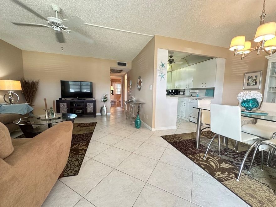 GREAT PRICE for this SPACIOUS 2 bedroom, 1.5 bath 1st fl condo located in a well-maintained 4 story bldg. Features an orig galley kit, tile flrs laid on the diagonal thru-out & ceiling fans in every rm. Primary bathrm has a shower stall w/glass shower doors. Enjoy the encl patio w/sliding plexiglass windows, exit door & roll-down shutters—plus the added benefit that outdoor brick patios are permitted! Being sold FULLY FURNISHED AS IS. Ideally located next to pool & tennis courts & close to Westgate. Excellent value & ready for your personal updates. Enjoy an ACTIVE ADULT LIFESTYLE in this gated comm w/24 hr sec, free busses, pools, tennis, pickleball, putting green, cafe, shuffleboard, AMAZING Clubhouse w/gym, theater, shows, billiards & more! DON'T MISS THIS OPPORTUNITY! ASSOC. CLAIMS 55+