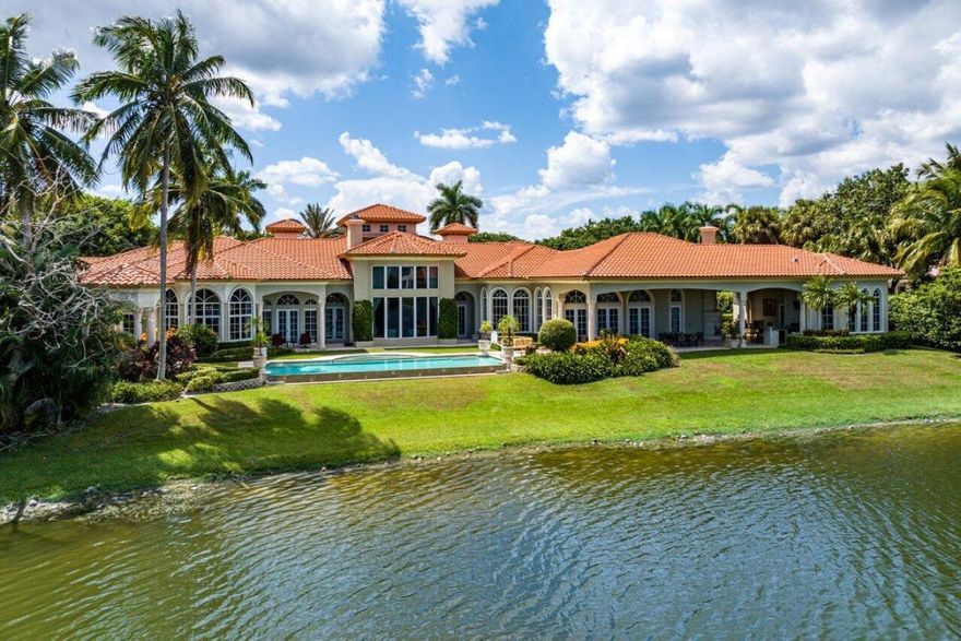 Breathtaking banyan trees welcome you to this majestic mediterranean lakefront estate boasting 10,013 square feet of living space and set on over an acre of meticulous and professionally designed landscaping. 8465 Twin Lake Drive is in a league of its own showcasing unparalleled luxury in one of Boca Raton's most coveted and exclusive neighborhoods, Long Lake Estates.  Designed for exquisite living and entertaining on a grand scale this custom sprawling property with extraordinary architectural details are evident in arched doorways, barrel and coffered ceilings, stone columns and custom millwork.  Featuring 7 oversized ensuite bedrooms including a guest house, staff quarters or in-law suite, 3 half bathrooms, club room with bar, home theatre, office and chef's kitchen this home is an entertainer's dream.  A private brick paved driveway leads to a huge circular motor court with porte-cochere. Flanking each side of the home are two 3 car garage bays. Two soothing fountains welcome you as you arrive to the grand custom front doors which are surrounded by glass panels and open into the 2-story foyer with 29 foot high ceilings.  The dramatic formal foyer leads to the sprawling living room and features coffered ceilings, floor-to-ceiling windows, a bespoke stone fireplace and is accompanied by dramatic lake views overlooking the infinity-edge pool. Enjoy a game of pool, play cards or watch a game in the handsome clubroom with custom millwork and built-in bar.  Stone columns frame the elegant formal dining room and adjacent to the dining room is the butler's pantry complete with a wine refrigerator.  A gourmet chef's kitchen is equipped for entertaining with top-tier appliances, center island with refrigerated drawers, counter seating and an adjoining generous breakfast enclave.  A light filled family room with hand painted ceilings plus 3 sets of french doors open to the gorgeous outdoor patio that overlooks the lake. Binge-watch your favorite shows in the cinema style theatre with Crestron home automation which can also be used as a safe room. The stately primary suite is spacious and serene with expansive lake views. A true retreat this primary bedroom has a sitting room, office and luxurious his and her bathrooms and dressing rooms.  The children's wing features 3 ensuite bedrooms and a lounge. Rounding out the first floor is a guest room and laundry room with two sets of washers and dryers and 3 half baths. The second floor is home to the in-law suite or staff's quarters with a kitchenette. With one of the finest lakefront lots available in Long Lake Estates the backyard is a majestic setting for year round entertaining.  Outdoor highlights include a spectacular loggia with gas fireplace, summer kitchen, dining and multiple seating areas. A sophisticated infinity edge pool and spa are add some glamour to the backyard. Take a walk down to the attached dock and enjoy the serenity and beauty of the lake. Unobstructed lake views, lush greenery and manicured landscaping make this one of a kind home the epitome of world class Boca Raton living.