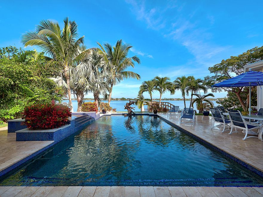 This exceptional 4 bedroom 4 bathroom home is ideally located on the loxahatchee river.  The gated 1000 ft driveway leads past the private boat launch with mooring dock and spacious 3 car garage to the brick-paver entrance of this truly rare, private and multifaceted home. French doors open to porcelain tile floors with mosaic inlay and coffered ceilings while the expansive water view beyond captivates the senses.  Formal dining, music/library and niches welcome you to the Open Kitchen and Family-room.  Custom built-in cabinetry and wood burning fireplace make this an ideal spot to relax and enjoy the river views.  The three (3) zone AC provides continuous comfort throughout the entire home. What a Great location for privacy and proximity to town.