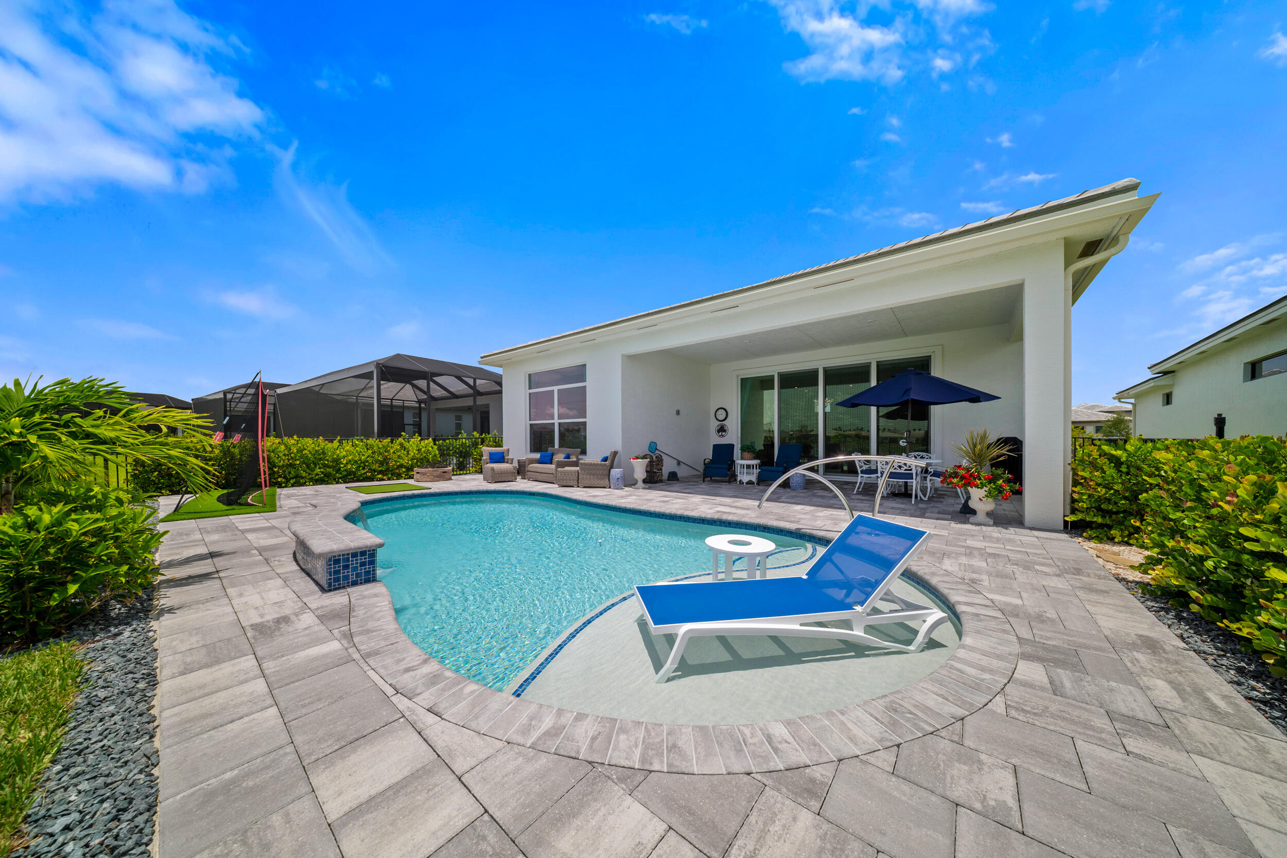PGA Verano! Young and Fabulous! You'll feel it the minute you walk in. 1 year new with a sunshelf pool. $100k+ of structural and architectural design upgrades! A calming, neutral color palette beckons you to relax under the soaring coffered ceilings. Grab a beverage and gather 'round the 10ft, 3'' thick quartz island that separates the chef's kitchen from the family and dining areas, with a gourmet appliance pkg and luxe cabinets. Head out through the 10 ft impact glass sliders to take in the lake view sunsets and wildlife. Dive in for a cooling dip under two 18'' waterfalls. A grand owners suite/spa-like bath with TV and expanded walk-in closet. Guests are treated to a private suite too! Golf cart access to PGA GC(memberships available)pickleball & Club Talavera keep you fit and social