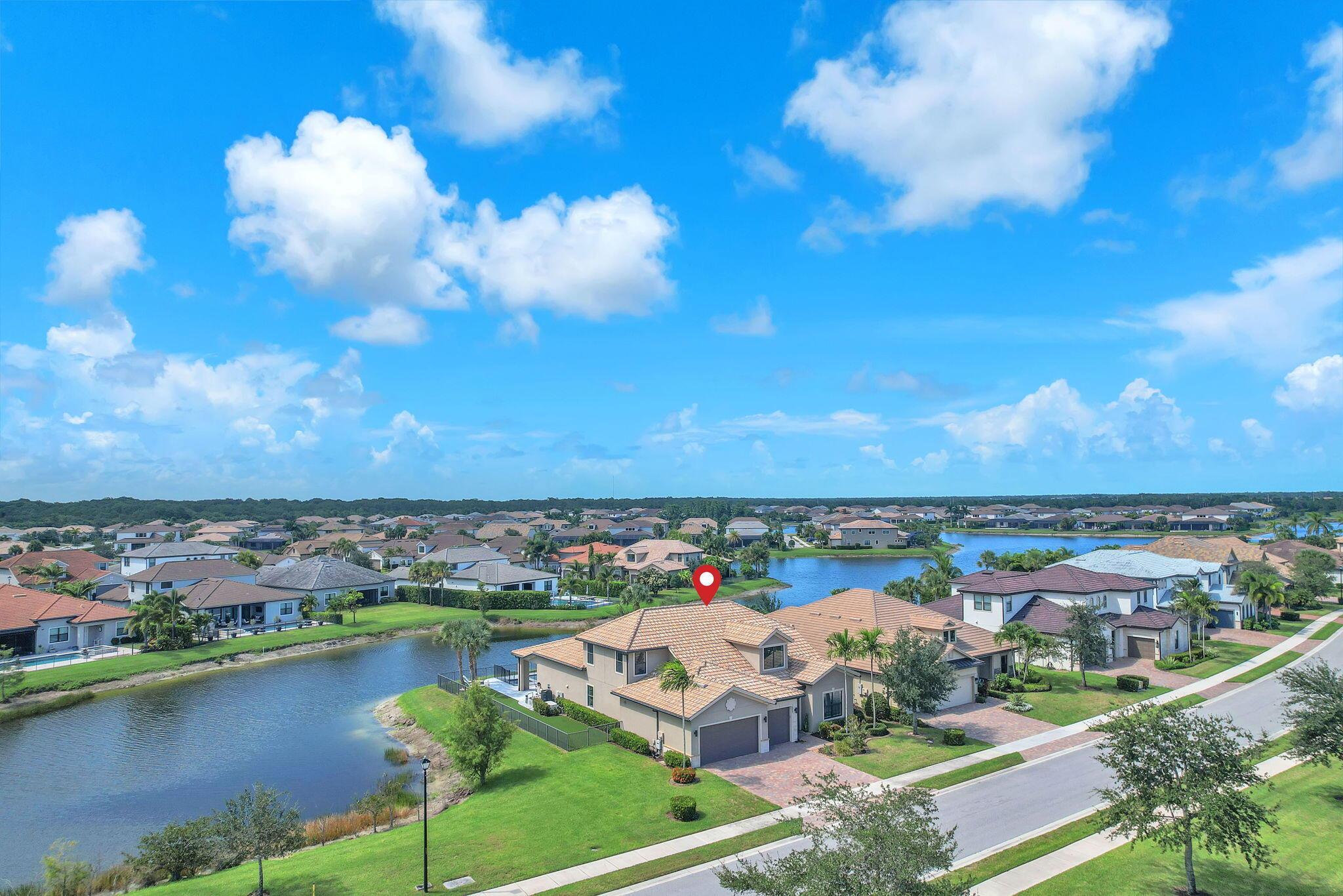 This stunning waterfront home, situated on a rare, ultra-premium corner lot, offers panoramic lake views from nearly every room. Enter through custom front doors into an elegant, contemporary residence featuring a spacious open floor plan and soaring ceilings that create an expansive feel. The chef's kitchen is a focal point, boasting gorgeous gray cabinetry, stainless steel appliances, a gas stovetop, double ovens, and a massive kitchen island. The home's modern flair is evident in its neutral color palette, upgraded wood-grain tile flooring downstairs, and dazzling light fixtures. The seamless indoor/outdoor flow between the living room and the patio makes this an entertainer's dream.