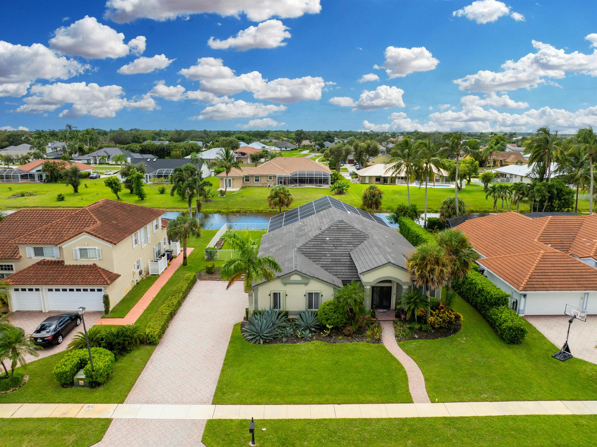 Welcome home to your exclusive gated community in the heart of Wellington, where low HOA fees, tranquil surroundings, and an A+ school district create the perfect setting for refined living. This beautifully maintained 4-bedroom, 2-bath waterfront home rests on a generous .29-acre lot and offers an inviting screened lanai with a covered patio, cabana bath, outdoor shower, and a beautifully updated pool--an ideal backdrop for both relaxation and entertaining. Inside, soaring volume ceilings and elegant tile floors complement an open design that flows seamlessly from the formal dining area to the chef's kitchen, appointed with granite countertops and premium stainless steel appliances.