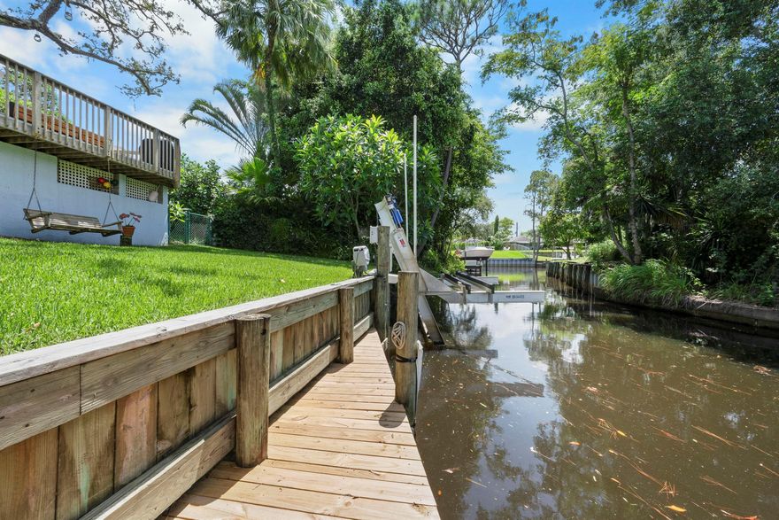 Palm City waterfront home w/ocean access in Rustic Hills. 15 minutes by boat to downtown Stuart and 25 minutes to the ocean, no fixed bridges. Includes a brand new 14,000 lb Hi-Tide remote control boat lift and a new dock w/electric and water. Craftsman-style home features 2 bedrooms plus an office that could serve as a third bedroom, pine floors, and nautical accents throughout, giving it a charming Martha's Vineyard feel. Enjoy the large Florida room and spacious deck overlooking lush landscaping and tranquil water views. Fully fenced private yard. No flood insurance required. Perfect for those looking for affordable waterfront living with character, ideal for boating and fishing. Excellent Palm City schools.  95' on water, 35' max on lift, 10' beam, 3 draft and no fixed bridges.