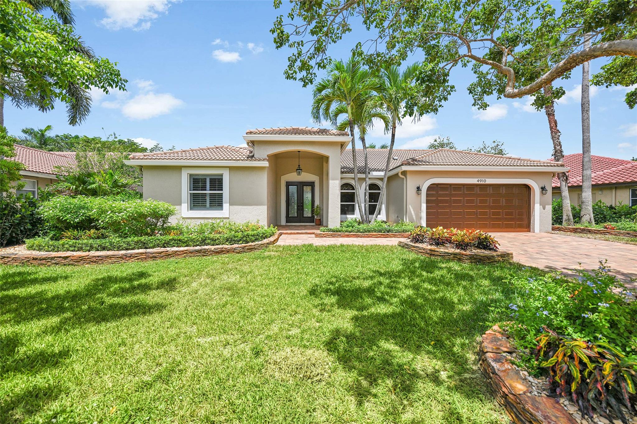 Beautifully upgraded home where the outdoors are just as impressive as the inside. Professionally landscaped with tropical flair, this meticulously maintained Split 5 bedroom 2.5 bath pool home features stunning custom stonework and tropical curb appeal. The seller has spared no expense in creating a beautifully landscaped oasis that makes a lasting first impression. From colorful crotons to hand-stacked stone beds, every detail is designed for beauty and ease of maintenance. New kitchen cabinets & appliances, plantation shutters, IMPACT GLASS windows & doors. tiled floors, solar sun shade. LED lighting, Large Primary Suite, Solar water heater. Low-maintenance rock beds and lush greenery, Perfect blend of design, function, and Florida charm. Great locations. HOA FEES JUST $625 PER YEAR
