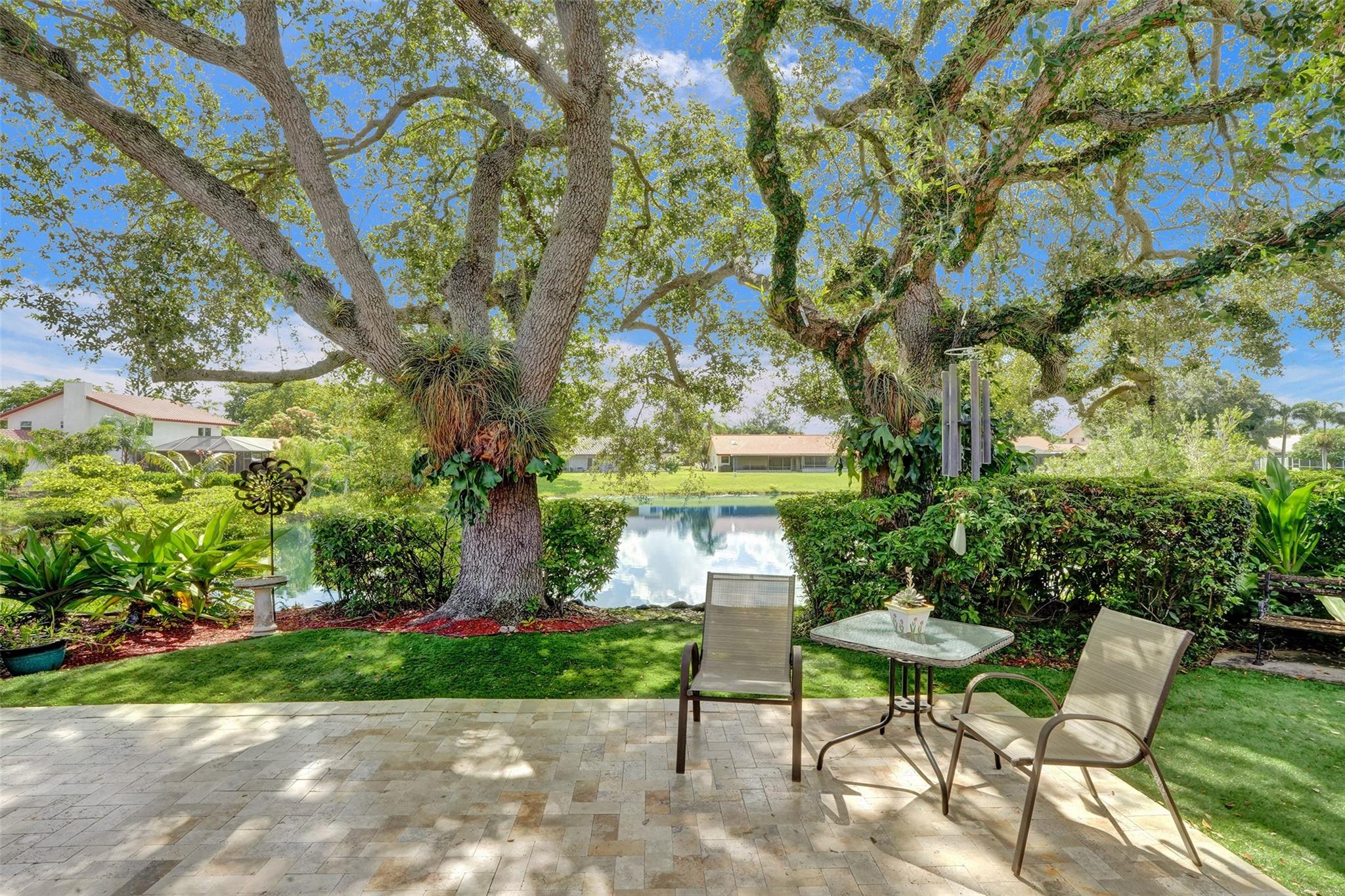 Experience peaceful lakefront living in this beautifully maintained 2/2 home with a 2 car garage, nestled on a perfect lot with stunning trees, serene water views, and a nice breeze. The backyard features travertine pavers, turf grass, and room for a pool. Perfect backyard for entertaining! This home has sliding glass doors in every rear facing room, offering natural light and relaxing views of the lake and backyard. Step out onto the screened in patio, the perfect place to enjoy your morning coffee or unwind in the evening. STANDOUT FEATURES: brand new floors throughout, freshly painted exterior , NEW AC 1yr, Vaulted ceilings, Walk in closets , fans in every room, split floor plan (great for privacy), spacious walk- in shower, accordion shutters, new community pool and TOP RATED SCHOOLS