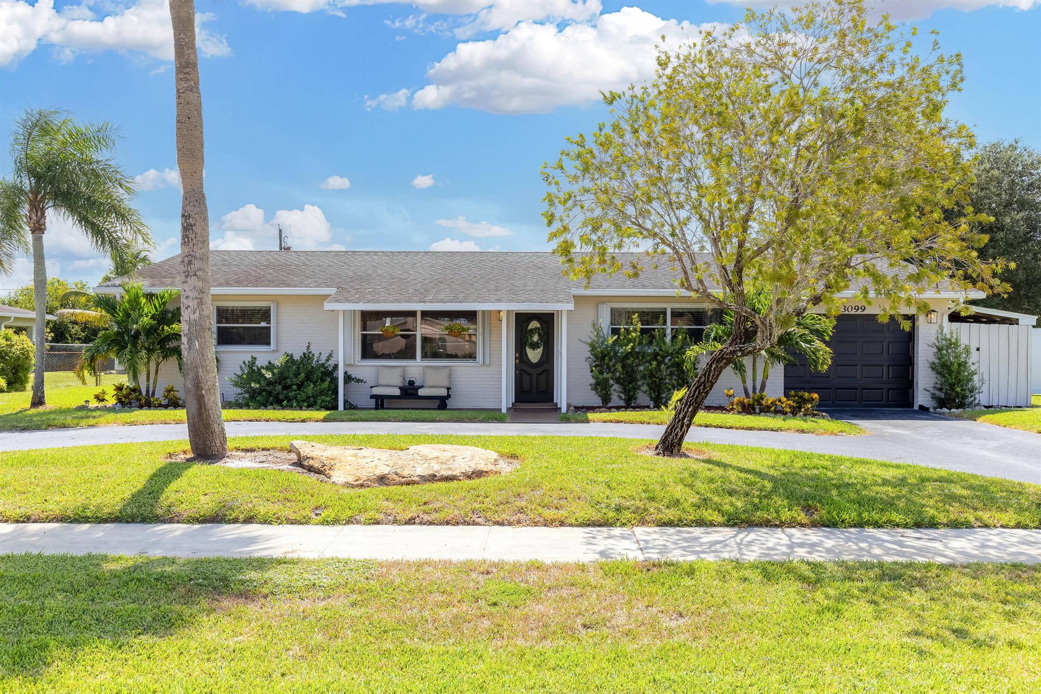Welcome to 3099 Medinah Circle E, a beautifully updated 3-bedroom, 2-bath pool home nestled in the heart of the Palm Beach National Golf and Country Club- a rare, no-HOA community centered around a public golf course in west Lake Worth. Step inside to discover an open floorplan and renovated interior with wood-look tile flooring throughout, high hat lighting, and a welcoming open layout. The updated kitchen shines with white soft-close cabinets, granite countertops, and stainless-steel appliances, perfect for both everyday living and entertaining. The bathrooms have been tastefully updated, and the home features a fireplace that adds a cozy ambiance--great for aesthetic charm or those rare chilly Florida nights. Additional highlights include a split floorplan, new A/C system, accordion