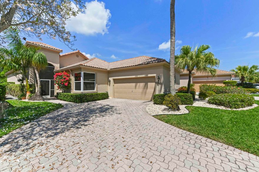 Welcome to your sun-drenched oasis in the heart of Boynton Beach. From the moment you pull into the elegant brick-paver driveway, this meticulously maintained residence captures the essence of sophisticated Florida living. Stepping through the screened entry, you are greeted by an expansive open-concept interior defined by soaring vaulted ceilings and an abundance of natural light streaming through strategically placed skylights. The seamless flow from the formal dining area to the spacious living room makes this home a natural choice for those who love to entertain or simply enjoy an airy, breathable atmosphere. The chef-inspired kitchen is a standout feature, boasting crisp white cabinetry, sleek stainless steel appliances, and stunning countertops that wrap around into a convenient breakfast bar. Whether you're enjoying coffee in the sunlit breakfast nook or preparing a gourmet meal, the view through the large windows remains a constant delight. Retreat to the primary suite, a true private sanctuary featuring direct access to the lanai and a massive walk-in closet with custom built-ins. The primary bathroom offers a spa-like experience with its deep soaking tub, separate glass-enclosed shower, and expansive vanity, ensuring every morning starts with a touch of luxury.  Beyond the sliding glass doors lies the home's crowning jewel: a sprawling screened-in lanai that offers breathtaking panoramic views of the shimmering lake and lush green fairways. Framed by majestic oak trees draped in Spanish moss, this outdoor space is perfect for quiet afternoons watching the world go by or enjoying the sunset over the water. With its perfect blend of modern interior upgrades and one of the most serene backdrops in the community, this home offers a lifestyle of unrivaled peace and beauty.
