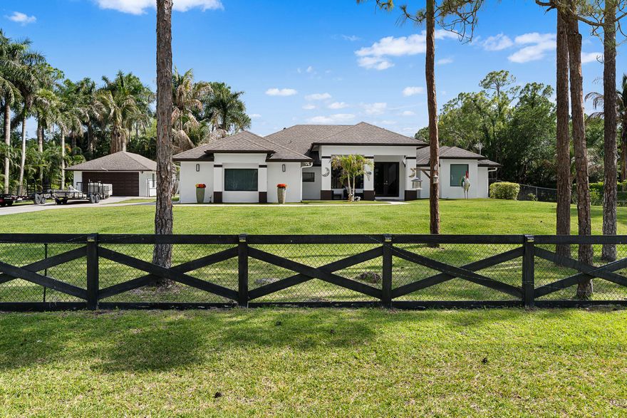 Turnkey estate living on 1.16 private acres in The Acreage with major upgrades already in place—2022 roof, 2024 A/C, and brand-new impact windows and doors (April 2026). Fully fenced, private, and move-in ready, this residence delivers both peace of mind and elevated living.  This fully upgraded property features a 3-bedroom, 2-bath main house offering 2,748 sq ft under air, a 2-car garage, and a detached 1-bedroom, 1-bath mother-in-law suite with its own kitchen and living area—ideal for guests or income potential.  Designed with a modern edge, the home features 48x48 porcelain tile throughout, open-concept living, and a sleek chef's kitchen with quartz countertops, high-gloss cabinetry, upgraded appliances, and an oversized 13-foot waterfall island.  Outdoor living is dialed in with a  saltwater pool and waterfall, expansive covered patio, and fully equipped summer kitchen with bar—built for year-round entertaining.