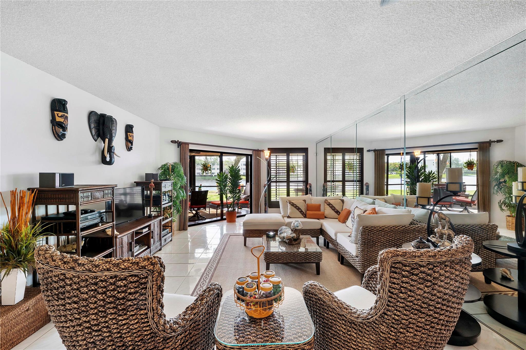 Immaculate, light-filled upgraded 2bed/2bath ground floor condo in the heart of Tamarac. Home entry way features 7 decorative walk way lights as you enter a lush flower garden. Interior features custom wood shutters, blinds, wood & woven wool treatments, granite countertops. Designer touch kitchen/dining fixtures, adjustable wall lighting, and ceiling fans throughout. Enjoy the scenic lake view perfect for relaxation. With accordion hurricane shutters (windows & patio), interior shutters for impact sliders in the sunroom, and screened exterior patio. Enjoy resort-style amenities: clubhouse, indoor/outdoor heated pools, tennis, pickleball, theater, fitness & art classes. One resident must be 55+. Move-in ready!