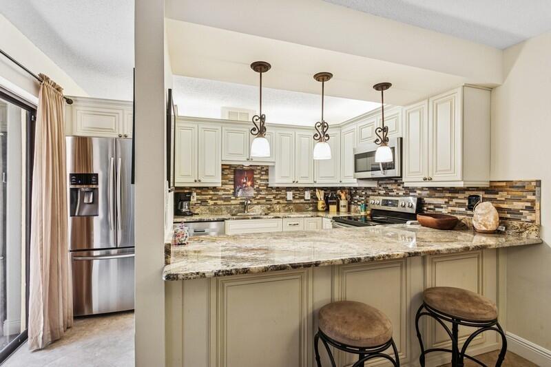 Enjoy the best of Florida living! Rarely Available Courtyard Townhome in The City of Atlantis! Experience a blend of comfort, privacy, and lifestyle in this 3-bedroom, 2.5-bath townhome located in the highly sought-after gated community of Atlantis. Tucked away in a quiet, lushly landscaped enclave, this spacious and beautifully maintained corner residence offers a well-designed living space with a balance of indoor-outdoor flow. Interior features a beautifully renovated kitchen with granite countertops, custom wood cabinetry, newer refrigerator, stove, microwave, and full-size washer/dryer. The main floor boasts 19'' tile flooring and a versatile 3rd bedroom for guests or home office, a convenient half bath and direct access to your private, fully fenced courtyard with pergola
