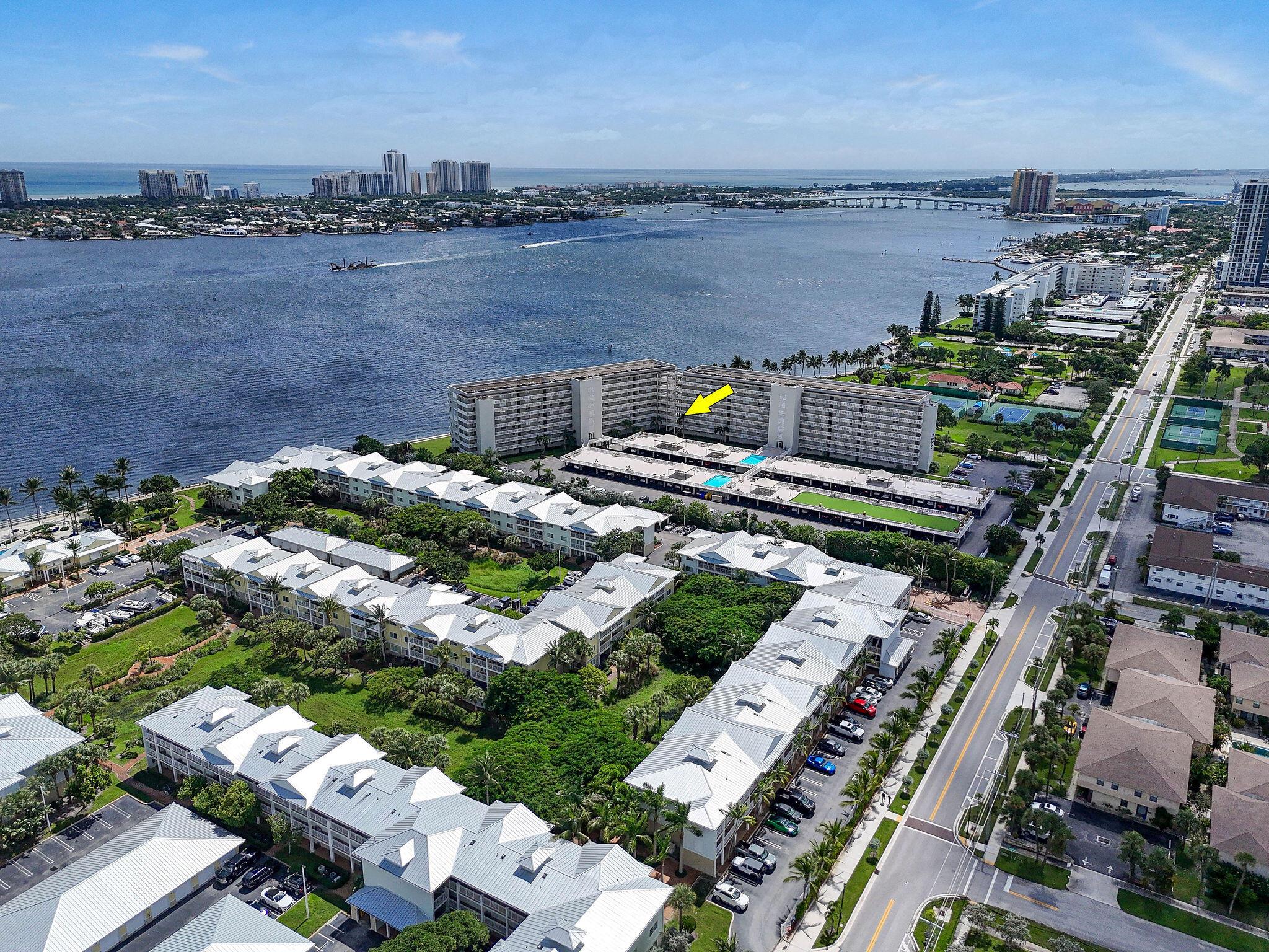 Sweeping Intracoastal views define this corner unit, showcasing gorgeous water vistas and glowing sunsets from most rooms. A private gated entrance, just off the exterior walkway, wraps around the residence beneath a covered balcony, drawing in breezes from the north, east, and south. Windows on three sides fill the home with natural light, enhancing its open-concept design. The kitchen features a peninsula-style counter with a broad seating surface, offering additional space for entertaining, along with extra storage cabinets below. A separate laundry closet with full-size WD, a pantry, and abundant updated dimmable lighting. The second bedroom is currently combined with a finished office. Flooring includes luxury vinyl plank, laminate, and tile. Plantation shutters throughout.