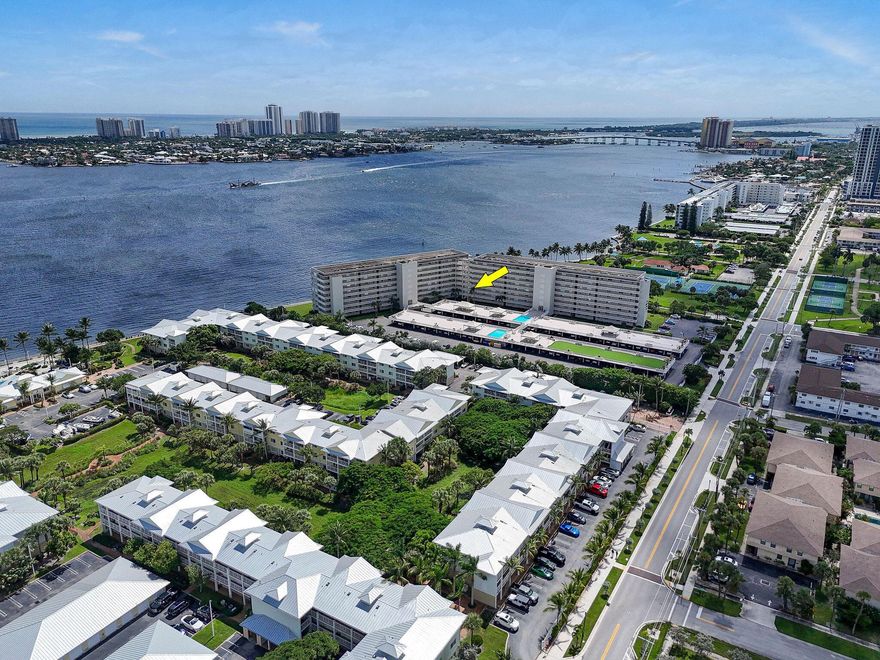 Sweeping Intracoastal views define this corner unit, showcasing gorgeous water vistas and glowing sunsets from most rooms. A private gated entrance, just off the exterior walkway, wraps around the residence beneath a covered balcony, drawing in breezes from the north, east, and south. Windows on three sides fill the home with natural light, enhancing its open-concept design. The kitchen features a peninsula-style counter with a broad seating surface, offering additional space for entertaining, along with extra storage cabinets below. A separate laundry closet with full-size WD, a pantry, and abundant updated dimmable lighting. The second bedroom is currently combined with a finished office. Flooring includes luxury vinyl plank, laminate, and tile. Plantation shutters throughout.