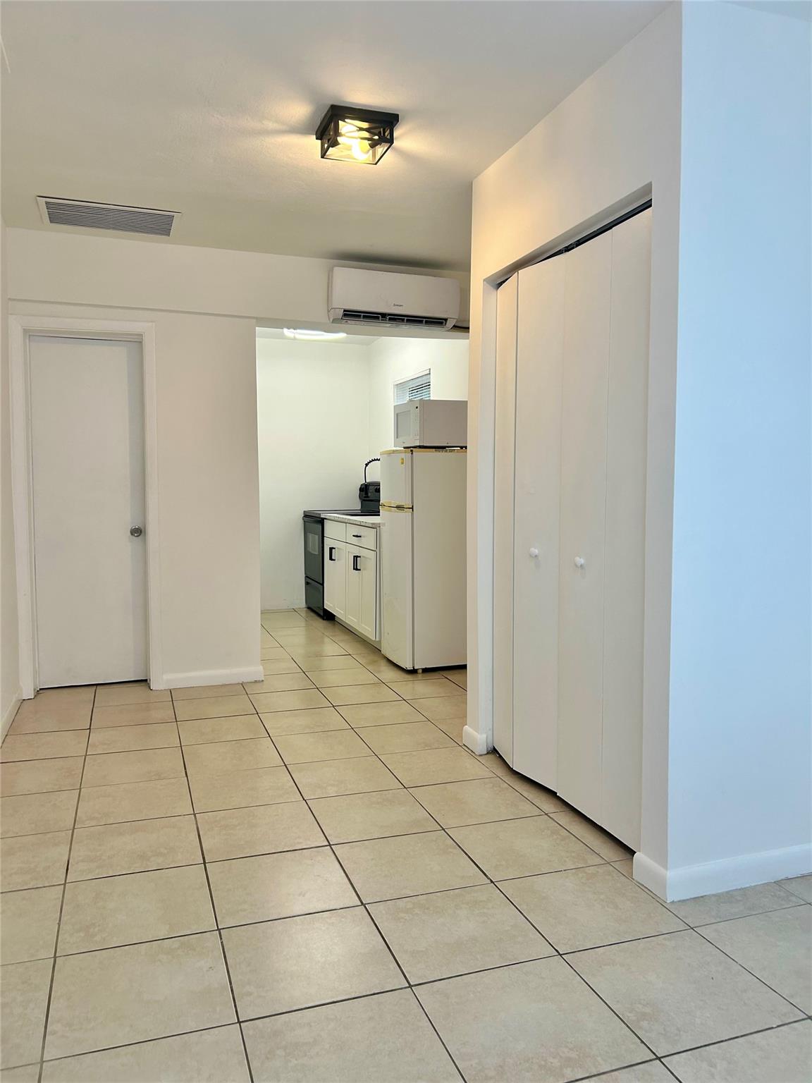 Freshly painted in crisp white, this luminous efficiency, attached to main house, features a brand-new kitchen with updated cabinets and countertop, plus essential appliances including new refrigerator, oven, and microwave. The space offers modern comfort with updated air conditioning, ceiling fans, and abundant natural light. Two convenient parking spaces. Electricity, water and sewer included in the rent. No condo approval needed. Ready to move in. Centrally located in a nice and quiet area.