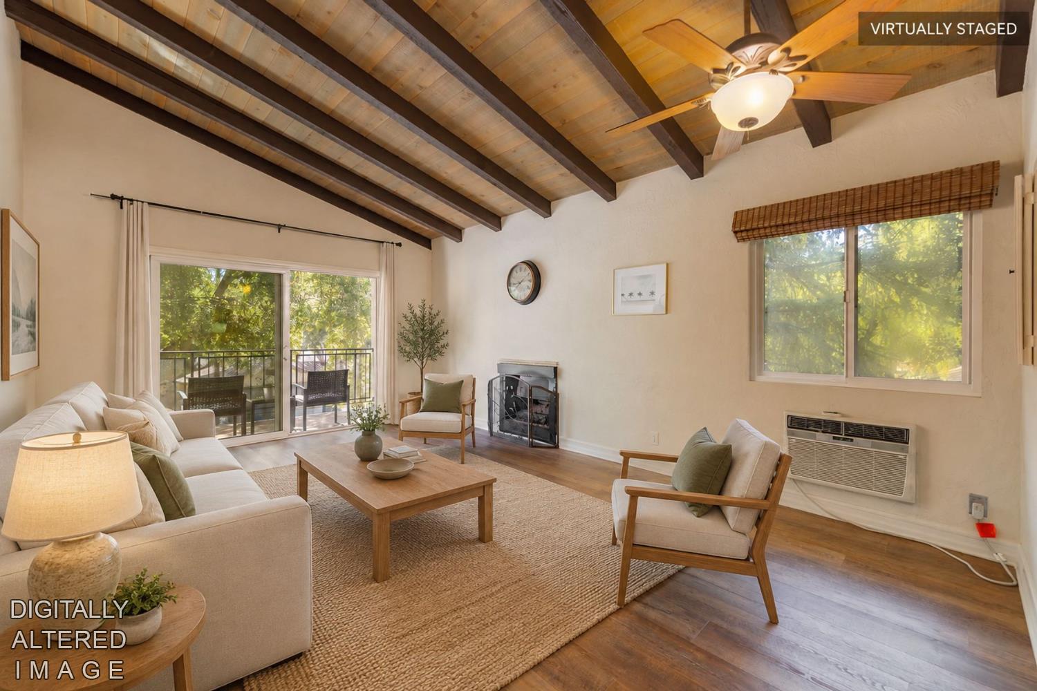Virtually staged living room with vaulted exposed-beam ceiling, fireplace, and sliding glass doors to a balcony.