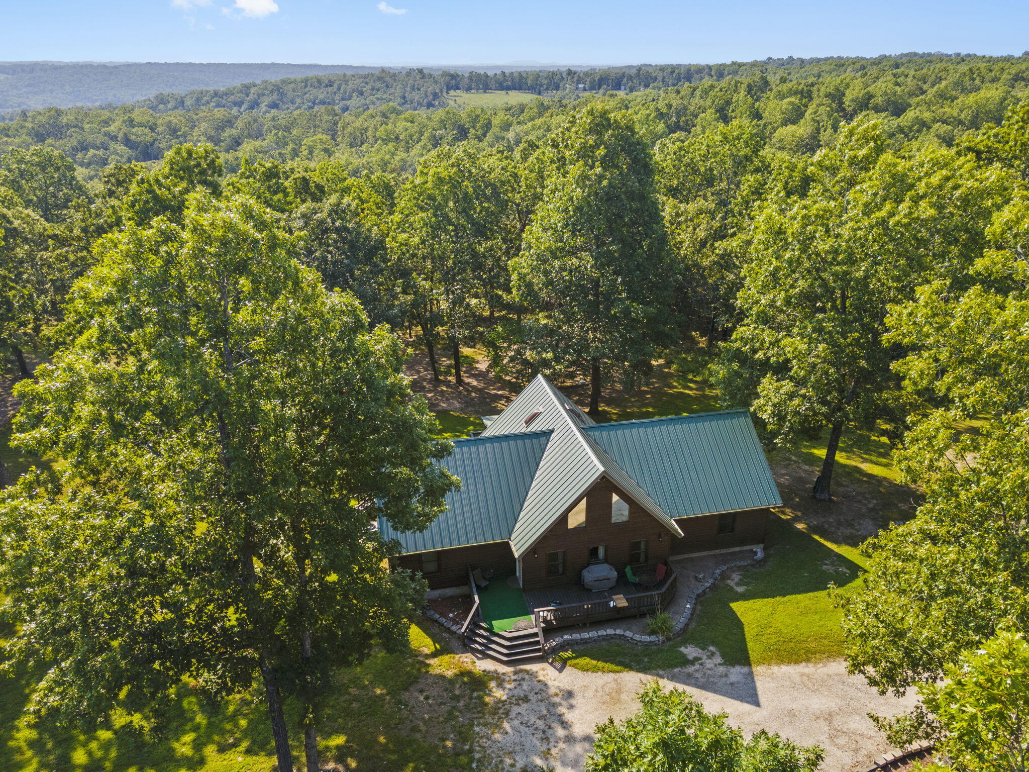 Discover your own 87-acre sanctuary, seamlessly blending comfort, luxury, and adventure. This wooded haven, with partially cleared areas, invites endless outdoor exploration. The home features four bedrooms (upstairs bedroom is non-conforming), and two beautifully remodeled bathrooms boasting a walk-in shower, elegant soaking tub, and stylish tile floors. Modern updates include newer windows, a patio door, updated lighting, a refreshed kitchen with granite counters, newer appliances, and a vaulted ceiling with exposed wood beams.Practical upgrades ensure peace of mind, like spray foam insulation, new gutters, a whole-house generator, a 3-year-old hidden-fastener metal roof, and a newer HVAC system. A cozy gas fireplace and an upstairs loft add charm, while big walk-in closets provide ample storage.Adventure awaits with miles of ATV and hiking trails, seasonal ponds, creeks, and abundant wildlife. The property also boasts a 50x30 insulated, air-conditioned RV garage/workshop, a four-car detached garage, and even a chicken coop. Located on Bull Shoals Lake with Corp of Engineers government frontage, this is the perfect retreat for those who seek tranquility without compromising on convenience. Don't let this rare opportunity slip away--your private paradise awaits!