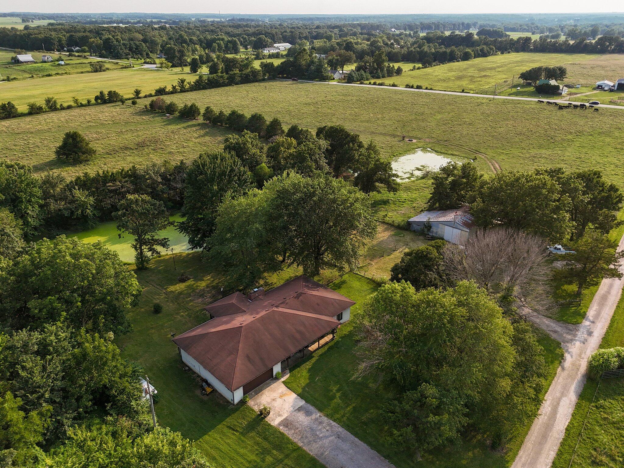 Welcome to 9414 E Clover Lane in Rogersville! This  picturesque  5-bedroom, 4-bathroom home spans over 4,000 sq ft and sits on 15 acres of fenced pasture, perfect for cattle or horses. Enjoy cozy evenings by one of the two wood-burning fireplaces or relax on the covered front porch and back covered deck, overlooking one of the two ponds. The upgraded kitchen boasts granite countertops and new cabinets, while the walk-in pantry offers ample storage. The basement kitchen can serve as a separate apartment. The property also features two living rooms for entertaining and an array of fruit trees, including pear, peach, cherry, and apple. Plus, a new Lennox HVAC system was installed in 2023- all electric which saves on your utility bill. Don't miss this incredible opportunity!