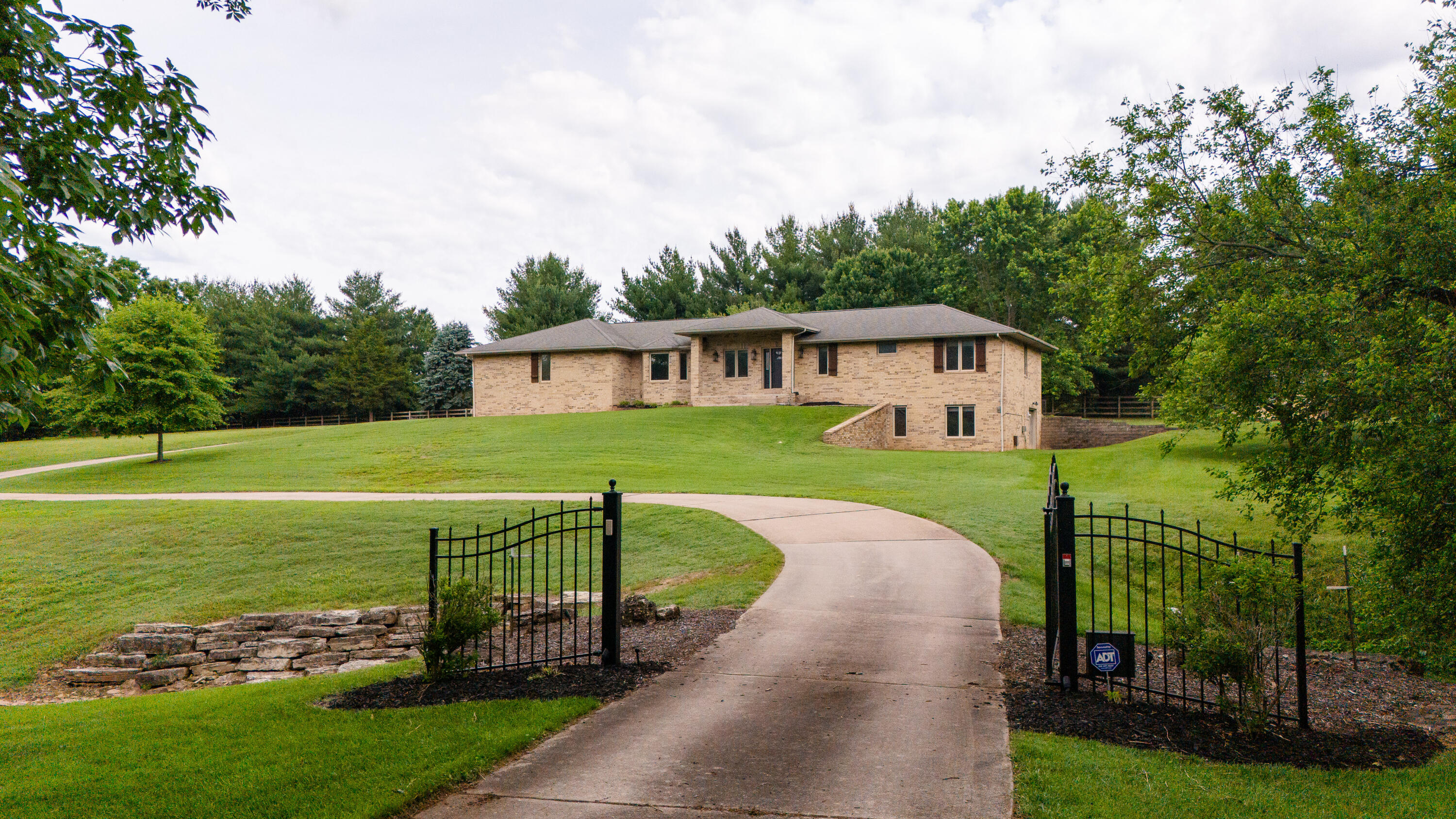 Come take a look at this all-brick beauty sitting on 3 acres in one of Springfield's most sought-after areas! On the first level you will find: first living room with a gas fireplace and hardwood flooring, kitchen with bar seating and a kitchen island, formal dining room looking over the peaceful acreage, one of two utility rooms, two bedrooms and two bathrooms.  The primary bedroom is on the main floor at back of home with a full master bath including: dual sinks, walk in closet, jetted tub, walk in shower and tiled floors. A secondary bedroom also located on this level and a full bathroom off the hallway with a tub-shower combo. To the basement: Large 2nd living area with a wet bar and room for additional appliances if wanted, two additional bedrooms, second oversized utility room with ample room for storage, mechanical room, another storage room, and home does have walkout access to east side of home. Basement could be used for in-law suite without any stairs on this level! Storage shed and the covered parking beside it will be staying with the home as well as washer, dryer, and refrigerator that are currently in the home. All doors are 32'' wide except for door under the staircase which is 28'' entry, and all are 6 panel! Home is on city water and private septic. Septic was just upgraded to accommodate a 5th bedroom should new buyer want to add on! Gate at entry does have a gate pad entry and also remotes that can operate it from the home. Roof is less than a year old. Come take a look you won't be disappointed!