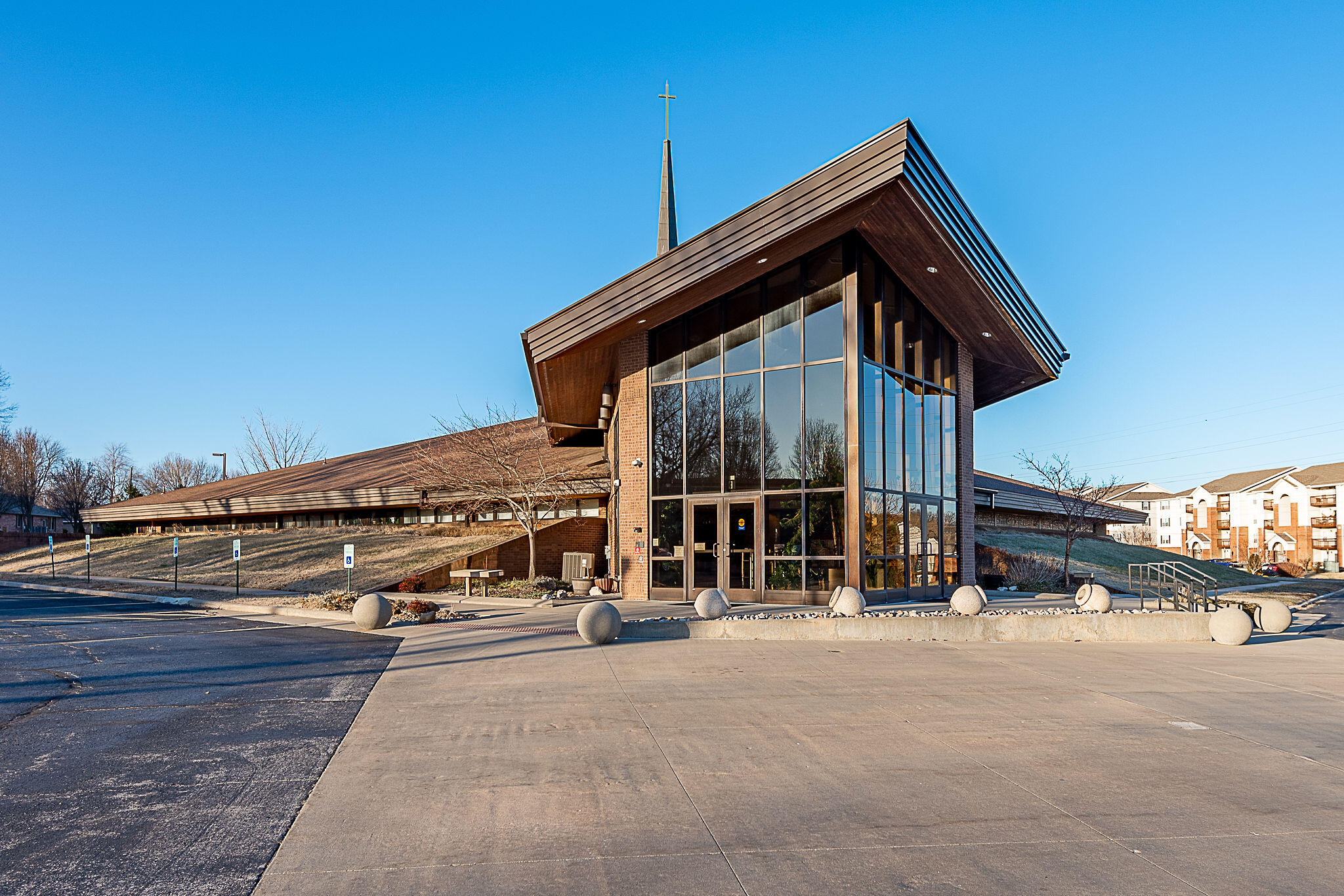 The main entrance features a striking two-story, angled glass lobby leading into the central corridor. To the right is the Sanctuary. To the left is a gathering area, Church and Pastor's Office, Work Room, Music Room with storage, Kitchen and public restrooms. The corridor extends north to the two-level Educational Building.Sanctuary/OfficesThe fan-shaped Sanctuary, seating 400, focuses on the Chancel area which is framed by stunning colorful stained-glass windows at the top of the exterior walls. A sloping ceiling enhances the uplifting atmosphere. At the back and above the corridor is the sound and lighting control area.The Corridor leads to the Educational Building, with an elevator and staircase providing access to the upper level. Near the stairs are boys' and girls' public restrooms, both with a shower, located on the main level and on the upper level.- West Corridor: Seven classrooms, each with vanity and sink, shared children's restrooms (in smaller kids classrooms).- East Corridor: Seven classrooms.- Commercial Kitchen is located on the main level next to the basketball court and Fellowship area.  - Second Floor: Mirrors the first floor with five (5) classes on the west and six (6) classes on the west and east corridor. A mechanical room is above the kitchen area.Additional Facilities- Youth Building is a two-story structure with a youth gathering space on the main level and storage above.- Recreational Area: A baseball field and Gaga Pit are at the rear of the property.Campbell United Methodist Church offers a thoughtfully designed space for worship, fellowship, education, and community activities.
