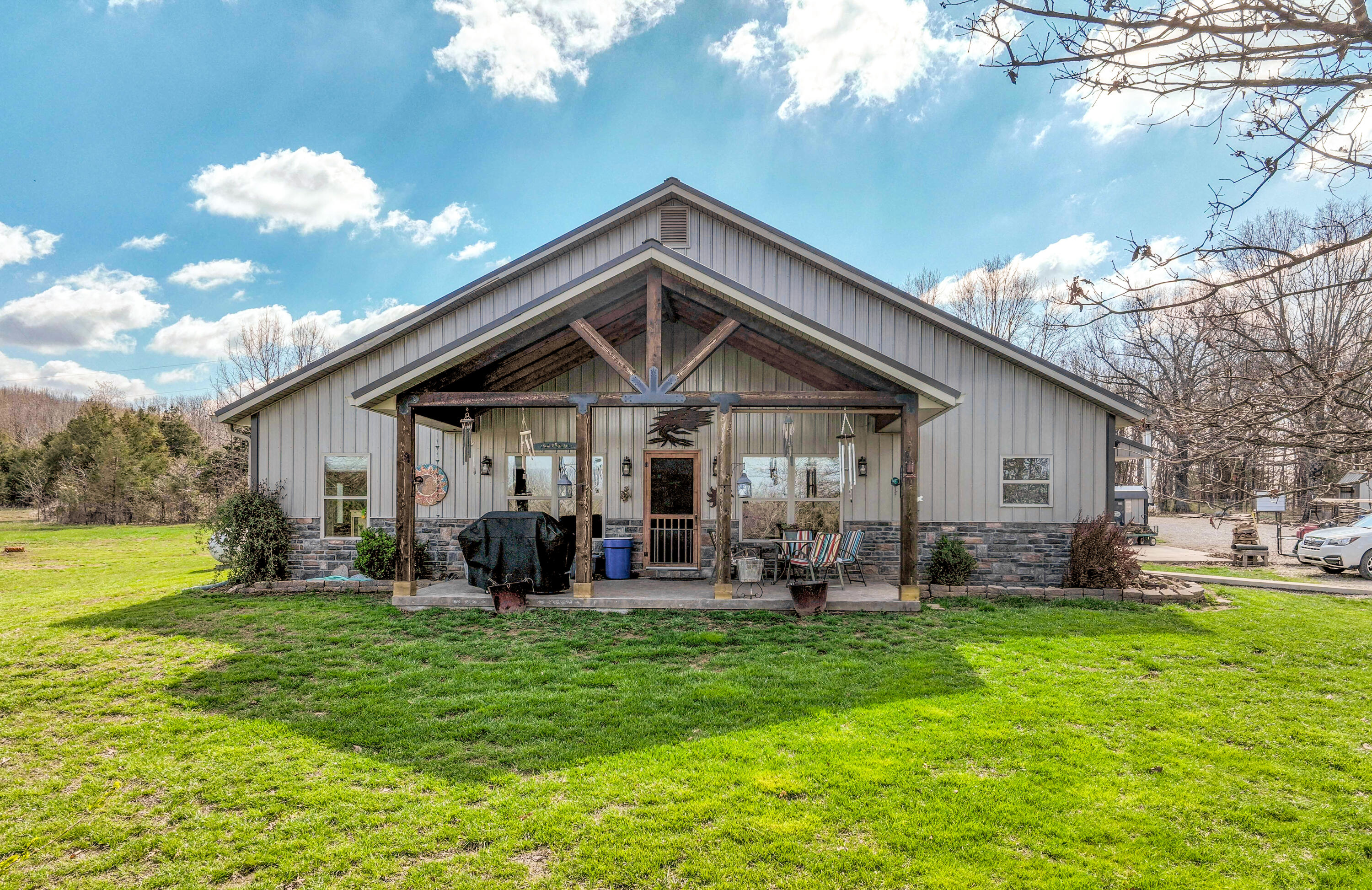 Country home for sale on acreage in the Southern Missouri Ozarks! Located near the town of Fordland, MO, this homestead has so much to offer from the spacious home to the mixture of open and wooded 18.83 surveyed acres m/l. The custom metal roofed and sided home welcomes you with its timber framed front porch, vaulted wood ceilings and open concept living space. With 4 bedrooms and 2.5 bathrooms, this home has a good flow and ample storage. Upon entering the home, the dining space and kitchen with a large island for barstool seating with granite counter tops lay to the right. Double ovens, cooktop with wood hood vent that extends all the way to the ceiling and an antique pantry door inviting you to store anything from appliances to drygoods.  The other half of the main living area features a floor to ceiling flagstone gas fireplace in the living room and what is currently being used as an office area with ample light brought by the large front windows.  The master suite is spacious with the master bathroom featuring both a walk-in shower, a soaking tub, and a vanity with double sinks.  The master bath wraps around to a large walk-in closet with organizers.  The concrete floors feature radiant heat supported by the outdoor wood burning boiler stove and back up propane furnace. The back up propane Generac generator gives you peace of mind. A pond, front field, fenced pasture and smaller fenced pen area for a variety of animals on this hobby farm from chickens, to pigs and cows.  Custom built shop and lean-to area allows for additional covered storage area. The shop is insulated and equipped with 220 power, concrete floors, extra storage room, potential office, and a half bathroom. The shop is heated and cooled making a comfortable work/hobby setting.  Additional outbuildings include a 2 bay open face machine shed and large RV carport with Hook-ups. Garden space, a hoop house, chicken house and chicken run complete this homestead.