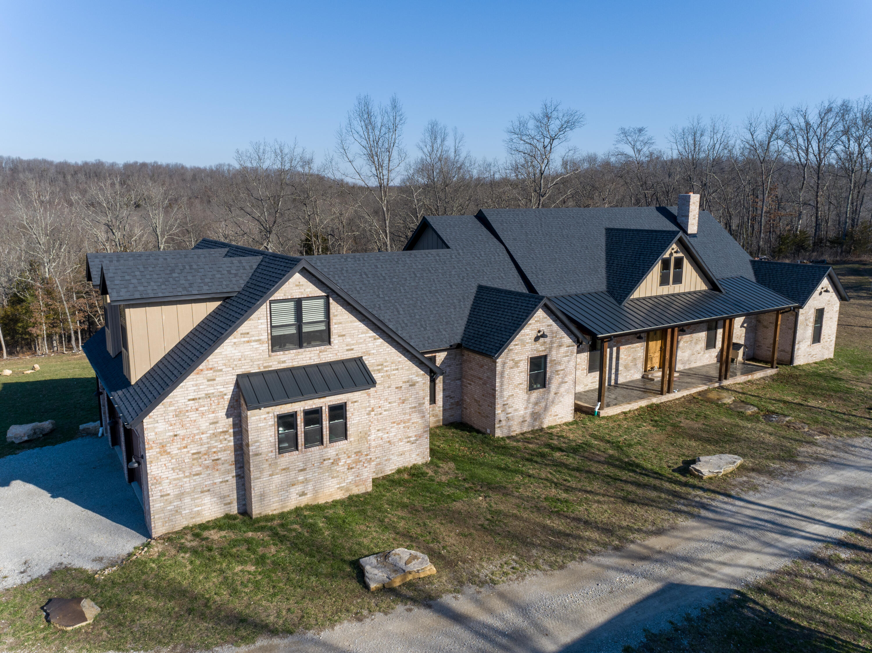Custom-quality brick home includes a 3000 sq ft. open floor plan with three bedrooms and 2.5 baths. The great room's focal point is a brick full masonry wood-burning fireplace, expansive vault ceiling, and skylights. The kitchen's custom wood house cabinetry has 52 in. upper cabinets, all soft closed with pull-out shelves on the lower cabinets. Quartz countertops, all Bosch appliances, propane oversized cooktop with pot filler, and a double oven including a speed cooker. Hardwood floors and 8 ft. custom knotty elder doors. Ceilings are 10 and 11 ft. with some very tall vaults. Divided floor plan; the master has a luxury bath and doors leading to the back screened-in porch. Two bedrooms have a jack-and-jill bath and an additional playroom or office. All bedrooms have walk-in closets. The family /game room is upstairs--large laundry room w/ wash sink, walk-in pantry, and a two-car attached garage. The whole house is networked. Speakers in ceilings in the great room and on the back porch. The screened back porch has a built-in propane grill and exhaust hood. The shop has 750 sq. ft. charming in-laws quarters/apartments with a private entrance. The shop area is fully insulated and drywalled with 12 ft drive-thru doors and a large open loft area for storage above the apartment. The greenhouse has water and electricity, and a raised bed garden is fenced to keep out wildlife.The chicken coop is 10x30 with a 20 ft. enclosed run. All this on 214 acres. If you are looking for a place to live that is secluded, peaceful, and quiet and where you can enjoy wildlife and spring waters, you have found the place. Bring the family; there is an in-law quarter with two bedrooms, where they can have their own space. Hiking, exploring, hunting, and relaxing in the country make the best place to live. About 20 min from Ava