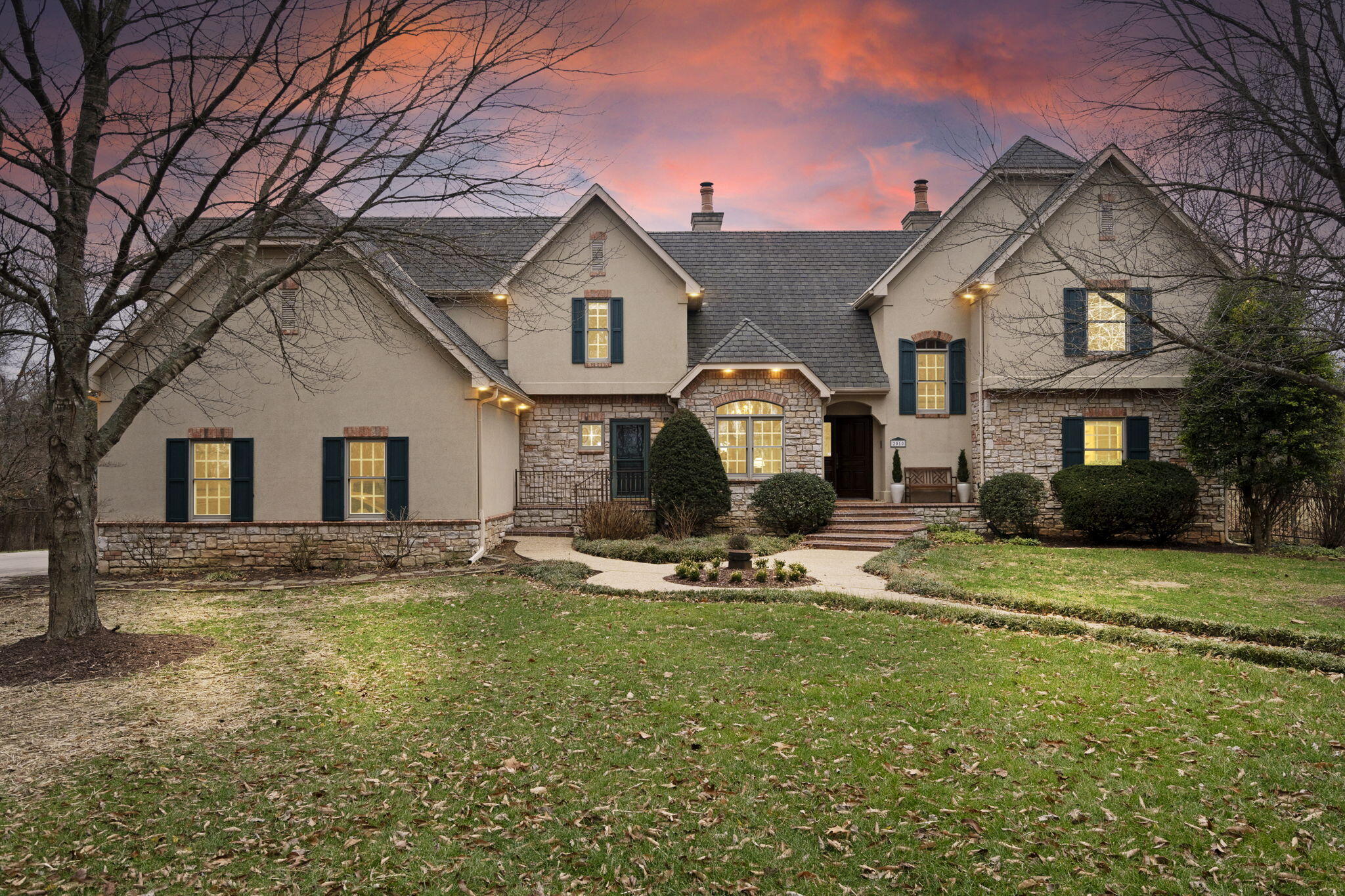 This beautifully detailed home at 2010 S. Shady Hill Ln offers an exceptional living experience. Located in a serene, private setting just under three miles from Hwy 65 & Sunshine, the property spans over 6 acres, providing a peaceful retreat while remaining close to Springfield's amenities. Upon entering the home, you're greeted by a lovely view through expansive windows, a vaulted ceiling, and a cozy gas fireplace, creating an inviting and relaxing atmosphere. The main floor features the primary bedroom suite with an updated bathroom that includes a jet tub, walk-in shower, walk-in closet, an enclosed toilet, and a dual vanity. The kitchen offers a generous number of cabinets, including a pantry, gas cooktop, and farmer's sink, with both a breakfast nook and a formal dining room nearby. Upstairs, two oversized bedrooms are connected by a Jack & Jill bath. The catwalk leads to a gorgeous office complete with built-in cabinets and a lighted tray ceiling, creating a sophisticated workspace. Adjacent to the office is a small kitchenette and full bath. A spacious bonus room is nearby, with ample storage and attic access. The back stairway offers easy access to the kitchen and side door, adding a practical option for office use or family convenience.The walk-out basement is a versatile space with a large living area, built-in cabinetry, and a wood stove. The full wet bar, complete with space for a table and full-sized refrigerator, creates an ideal space for gatherings. Two additional large bedrooms and a full bath complete the lower level. The John Deere room, with over 600 square feet of space, houses two furnaces and two instant gas water heaters. On the main floor, a large deck with a pergola overlooks a small wooded area, providing a tranquil space to enjoy the outdoors, complete with a firepit. Situated at the end of a private road, this home offers incredible privacy and is designed with quality craftsmanship by Michael Dee Smith