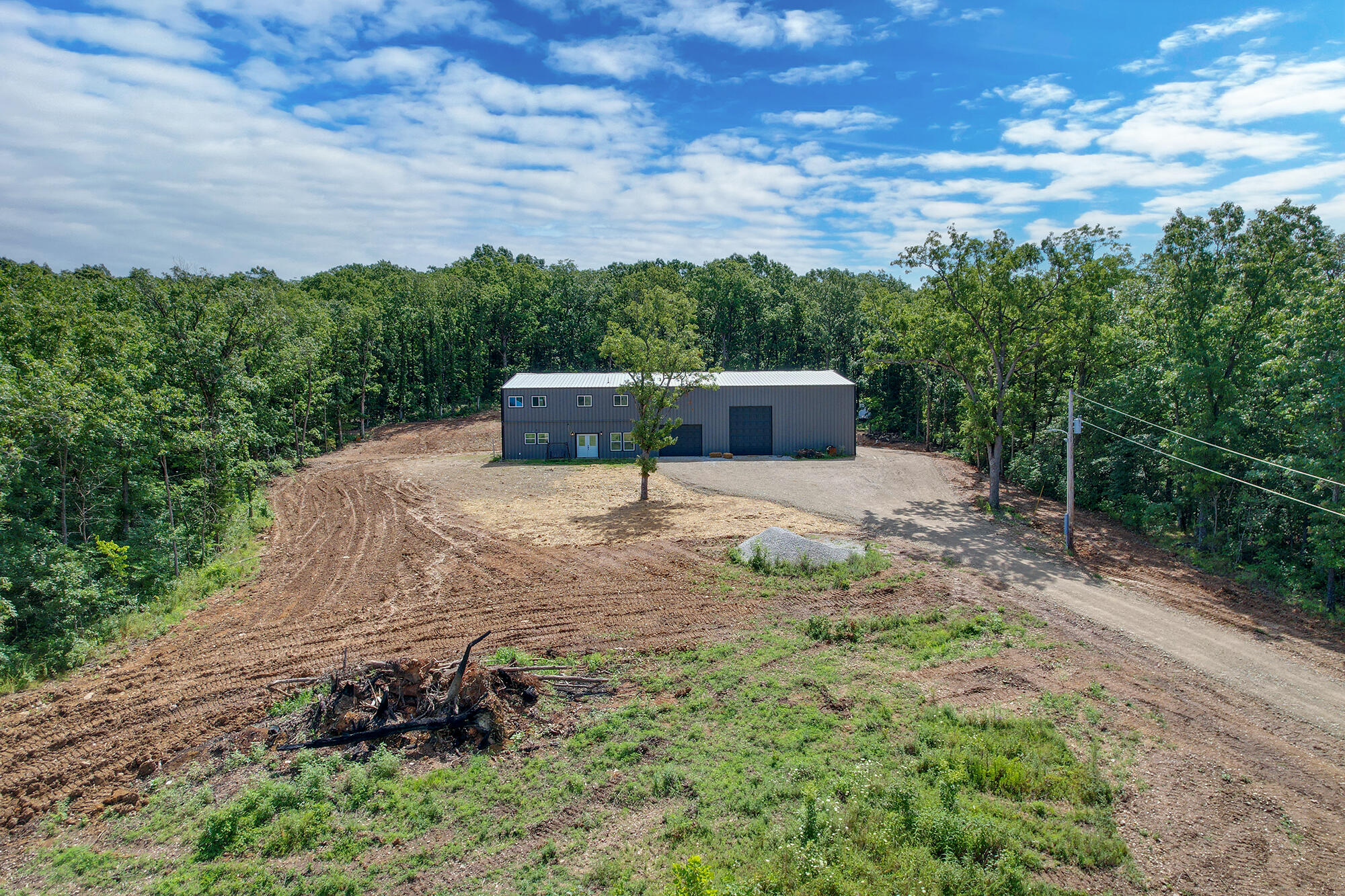 Imagine yourself watching the sunset from your 4200 sq ft 6 bd/3ba home. This barniminium is ready for you to make it your own. With spray foam insulation, this home is very energy efficient. With its 6 bedrooms, with 2 of them being non-conforming due to the absence of closets, there is plenty of room for family and guests. These rooms can still be utilized as media rooms or offices, offering versatile spaces to suit your needs. The large open floor plan is perfect for entertaining, featuring a spacious kitchen with a large island ideal for seating and preparing family meals. Imagine hosting gatherings in this inviting space, where laughter and conversation flow seamlessly. The open staircase leads to an expansive family room and four additional bedrooms, providing ample space for everyone. The shop side of the house is a standout feature, measuring 60x60 with three overhead shop doors, offering abundant space for storage and projects out of the weather. The shop also has 450 amp electric service with a 50 amp RV hookup. The 40 acres of land with trails includes a pond and an abundance of deer and wildlife, making it a nature lover's paradise. Not to mention the sunsets! AMAZING!!