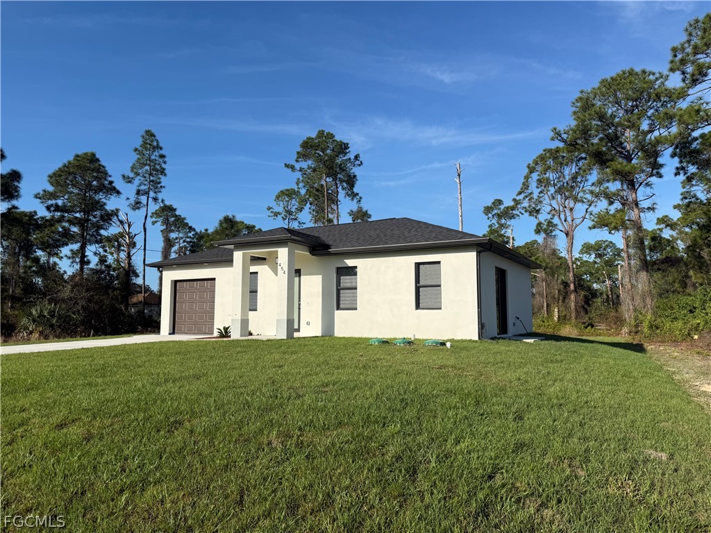 View of front facade with stucco siding, a front y