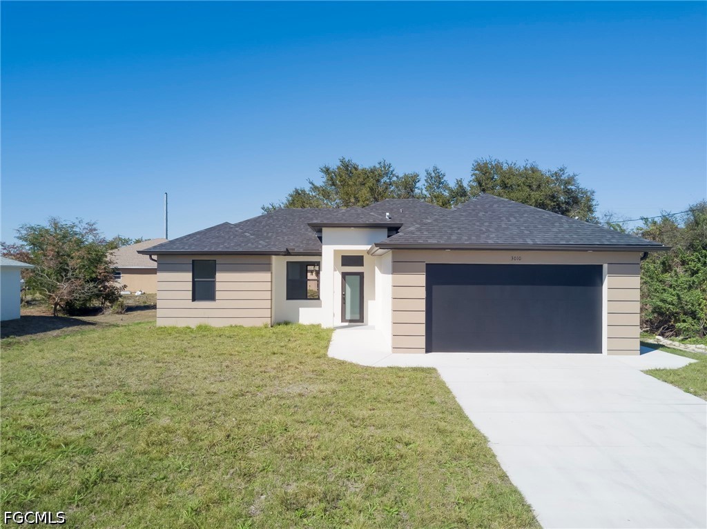 Prairie-style house featuring a front lawn, a gara