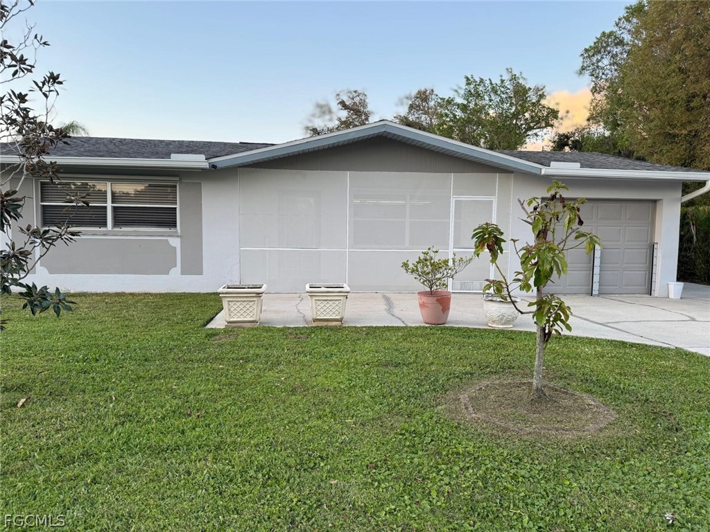 Ranch-style home featuring a front lawn, an attach
