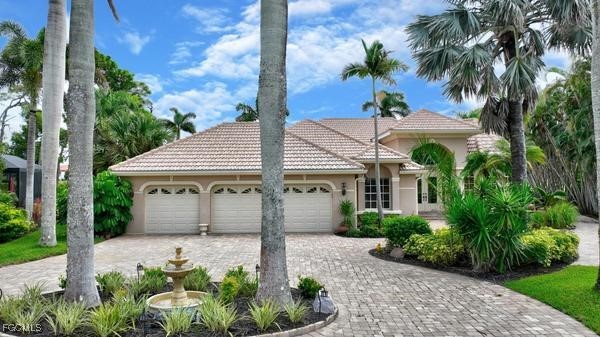 View of front of property with a tiled roof, a gar