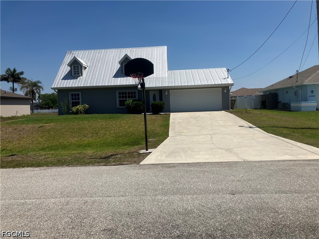 View of front of home with a metal roof, a front y
