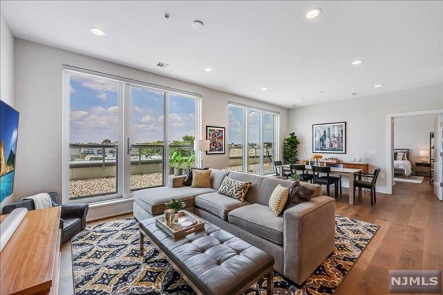 Welcome to Palisade Square, a mid-rise steel and concrete elevator building offering high-end luxury. This bright, spacious 1624 sq ft, 3 bedroom 2.5 bathroom duplex has it all with outdoor space and parking and meticulous design, highlighted by a wall of windows with sunset views and featuring hardwood floors, over 9.5 ft ceilings, and oversized windows with access to an outdoor terrace. The kitchen showcases top-of-the-line Kitchen-Aid appliances, brand-new custom wood cabinetry, quartz countertops, ceramic tile backsplash - and additional storage cabinets in the island. The primary bedroom has a large custom-built walk-in closet. Contemporary fixtures and Porcelanosa tiles adorn the primary bathroom, including heated floors, double vanities, quartz countertops, Moen 90 Degree bath fixtures, and glass shower doors. Upstairs are two generously sized bedrooms bathed in natural light and a elegant bathroom with a tub. Additional features include an in-unit full-size washer and drye