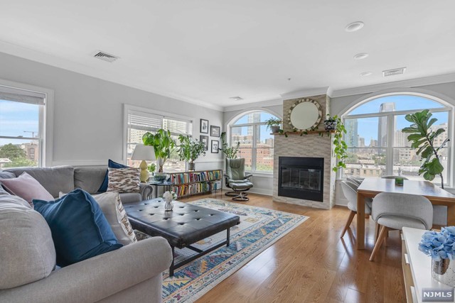 This exceptional home features an open layout with spectacular downtown Jersey City and NYC views. Currently used as 3 bedrooms, this home offers 2 bedrooms plus a den and 2.5 baths. Spacious and bright, this Penthouse is adorned with skylights throughout. Chef's kitchen is equipped with GE Monogram series appliances, quartz counters & center island. Living room boasts an impressive floor-to-ceiling tiled gas fireplace & over sized windows that provide incredible north and easterly views. Located in the heart of Downtown JC's historic district, a block from Van Vorst Park and near the Grove ST PATH, Light Rail, as well as nightlife & restaurants. Common amenities include a Peloton bike and exercise studio, an elevator, and a manicured backyard. A full-size, deeded indoor garage parking spot with space for storage is included for your convenience. Don't miss the opportunity to own this exquisite penthouse!