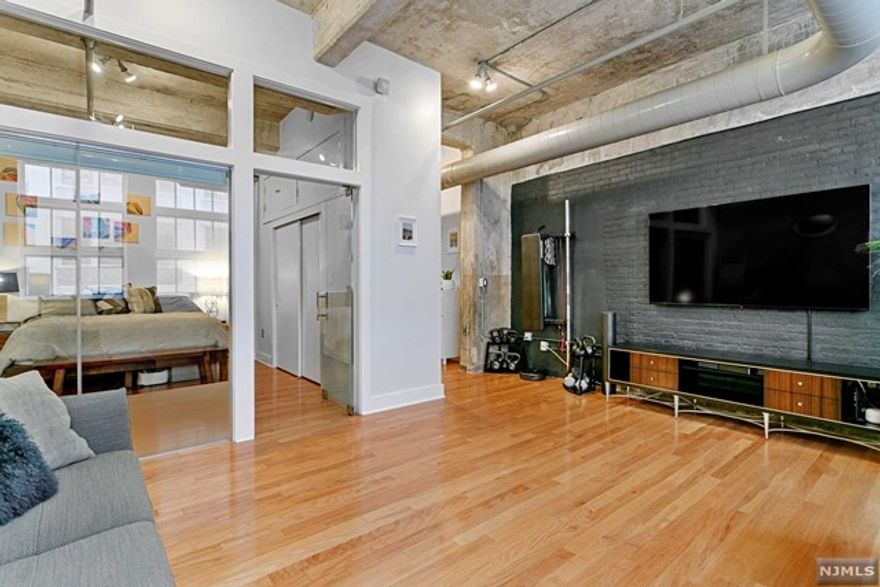 True Urban Loft w/unique qualities & swank at rare Cooke Lofts. Defined by original details & stunning industrial flair such as concrete columns & high ceilings, exposed ducts, large commercial windows for authentic loft living. 3E is a spatially versatile 950sf floorplan for Work & Live Space. Glass wall partition & door creates dynamic visual between living area & bedroom. Galley kitchen w/white cabinets, granite counters & new glass tile backsplash. Entry foyer flows to office/work area. Remodeled modern BA, HWF, CAC/heat, W/D closet, Google Nest smart thermostat system, electronic smart blinds in living area, Philips Hue smart lights in living area and BR, and upgraded Elfa storage closet. The Cooke Lofts DTJC's most singular boutique style loft building w/recently renovated large entry lobby reminiscent of its history & a large common roof deck in Powerhouse Arts District, DTJC's vibrant neighborhood by Grove PATH easy NYC commute & access to plentiful dining & retail nearby