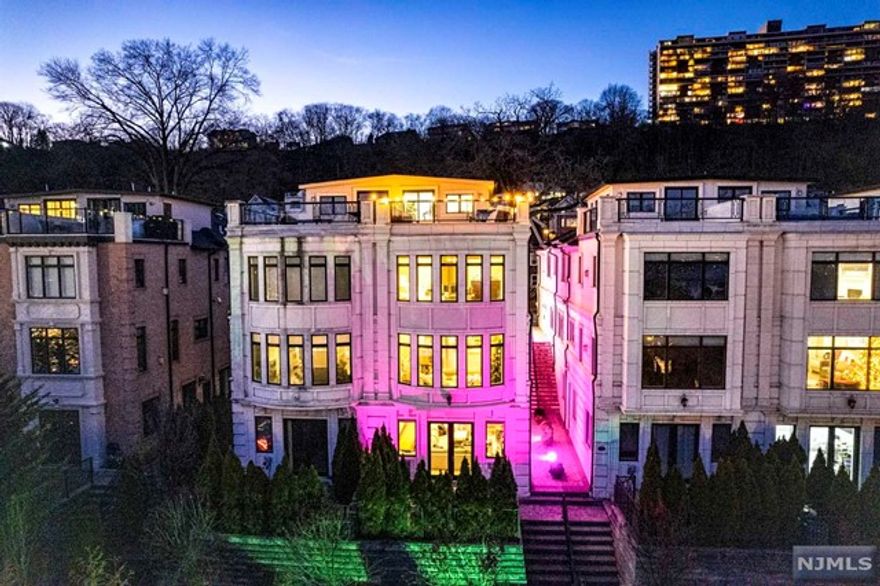 Exceptional home (approx 4,800 sq ft) is built like a fortress with the finest materials and ornate architecture: From the smooth limestone like exterior, with ornate cornices, to the giant beveled windows. The inside still feels brand new & has beautiful trim work throughout: custom chair rail paneling, new wall covering in DR, vaulted ceilings above, and sconces all throughout. The kitchen is simply gorgeous: all white w/high end appliances incl. 36" range w/SS hood (vents outside) w/a large center island. It opens to a large den adorned w/ large windows. The PS is fit for an executive with FPL, cove lighting, large walk in closets and luxurious marble bathroom and a 6"ft Jacuzzi + walk in shower. The lower level w/10"ft ceilings has an enormous family room, en-suite, and French doors to patio and yard. The top floor has a great entertainment room w/wet bar, 1/2 bath, & roof deck w/GW bridge + NYC & river views. Very easy commute to NYC via Ferry or Bus or Car.