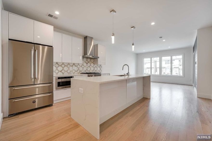 Welcome to this luxurious 1700+ sq foot condo in the highly sought after Jersey City Heights! This 3 bed 2 bath condo is all new construction and features a beautiful and serene private backyard. The custom chef's kitchen is complete with Bertazzoni appliances, quartz countertops with waterfall Moen faucet, European style frame less cabinets and 4" solid hardwood flooring. The open floor plan in the kitchen and bright spacious living room allow for great entertainment space. The beautifully updated bathroom boasts frameless shower doors and rain shower head as well as a double sink vanity. This unit features a modern design throughout, energy efficient full spray foam insulation, separate private entrance, additional private storage and parking spot in the attached garage! Plus, a central Vacuum system, Andersen windows, Rheem HVAC, sound dampening rubber member between floors for sound insulation. Don't miss the opportunity to own this fabulous unit!