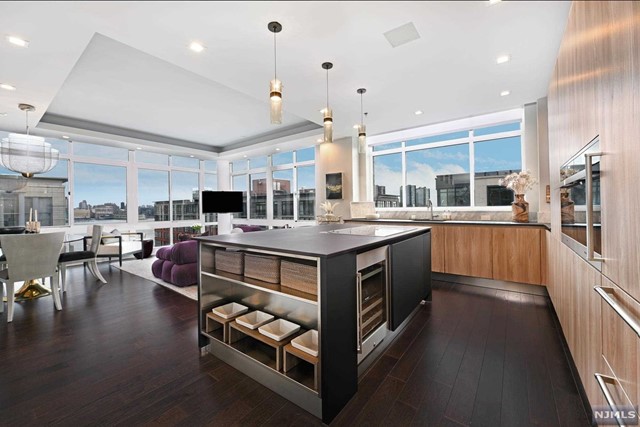 Stunning SE facing 2 bedroom 2 bath corner Penthouse with NYC views in the luxury waterfront Maxwell Complex. This spectacularly customized and upgraded home strikes an inviting balance of warmth and comfort in a modern aesthetic and was featured in Design NJ, highlighting its beautiful and sophisticated kitchen redesign overseen by Mimi&Hill of Westfield. Appointed with Arclinea cabinets, Dekton countertops, Carrera marble backsplash, Miele appliances including induction cooktop, downdraft exhaust, 2 wall ovens- conventional/convection and convection/steam, SubZero refrigerator and Gaggenau dual zone wine cooler, this fabulous kitchen is as chic as it is chef worthy. Raised ceiling heights in the kitchen and the living room, with tray ceiling and custom cove lighting, add to the open loft-like feel with a bespoke built-in dining banquette with Moooi chandelier enhancing this exceptional space. An en suite oversized primary bedroom has soundproofing to ensure peaceful rest.
