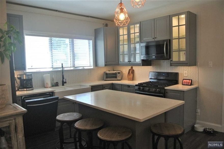 Beautifully updated 1st floor unit with 9 feet high ceiling. Open layout with Living room, formal dining room, grand kitchen with island, SS appliances- double oven, refrigerator, microwave, dishwasher, new bath with marble floor and wall tiles. Barn door between living room and dining room (possible 2nd bedroom). Panel floor, washer/dryer, use of yard with wooden patio great for entertainment, driveway for 2-3 cars(1 car width).Additional storage in an attic. Dog permitted on premises. Conveniently located, close to NYC transportation.