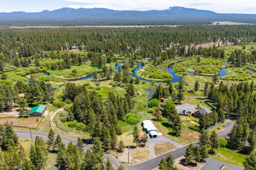Million dollar river views for a fraction of the price! Imagine waking up to panoramic views of the Little Deschutes River and Paulina Peak right from your doorstep. This light-filled home offers nearly 500 feet of river frontage, perfect for kayaking, paddleboarding, or canoeing. Your riverfront retreat comes with nearly 4 acres of serene nature-filled privacy. A haven for wildlife, you'll see deer, quail, elk, porcupines, beavers + playful river otters right out your front door. New stainless steel appliances, flooring, updated light fixtures, and fresh interior and exterior paint. An open concept living + dining room offers gathering spaces for everyone - cuddle up in front of the cozy wood stove or laze in the afternoon sun on the freshly-refinished deck or along the river. Located on a corner lot in a quiet cul-de sac on a paved road with a single car garage, 240 SF multi-use outbuilding, and room for a shop! Quail Run Golf Course, Mt. Bachelor and Newberry Crater are all nearby!