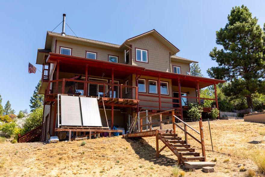 Beautiful custom built 3 bedroom, 2 bath 1849 sf home.  This home sits on 2 spacious acres with incredible views of the lake and mountains. The quality is shown by having radiant solar heated floors and hot water, Italian porcelain tile, Cambria quartz counters, red Travertine & copper slate bathrooms/showers. Covered deck off main floor is perfect for your relaxing and entertaining. Open living room with two stories of custom windows and an upstairs loft for your enjoyment. Master bedroom has a beautiful propane fireplace and a Mitsubishi air conditioner/heater as well as a jetted soaking tub. Current owners seldom have an electricity bill due to the 4.8  Kw Pv solar system  on revenue generating contract. Last year they received more back than they paid for electricity.  Detached wood shed, large insulated finished 952 sf shop/ garage with an upstairs previously used as a music/art room with composting toilet.  Two fenced garden areas plus more than 1/2 acre perimeter fencing.